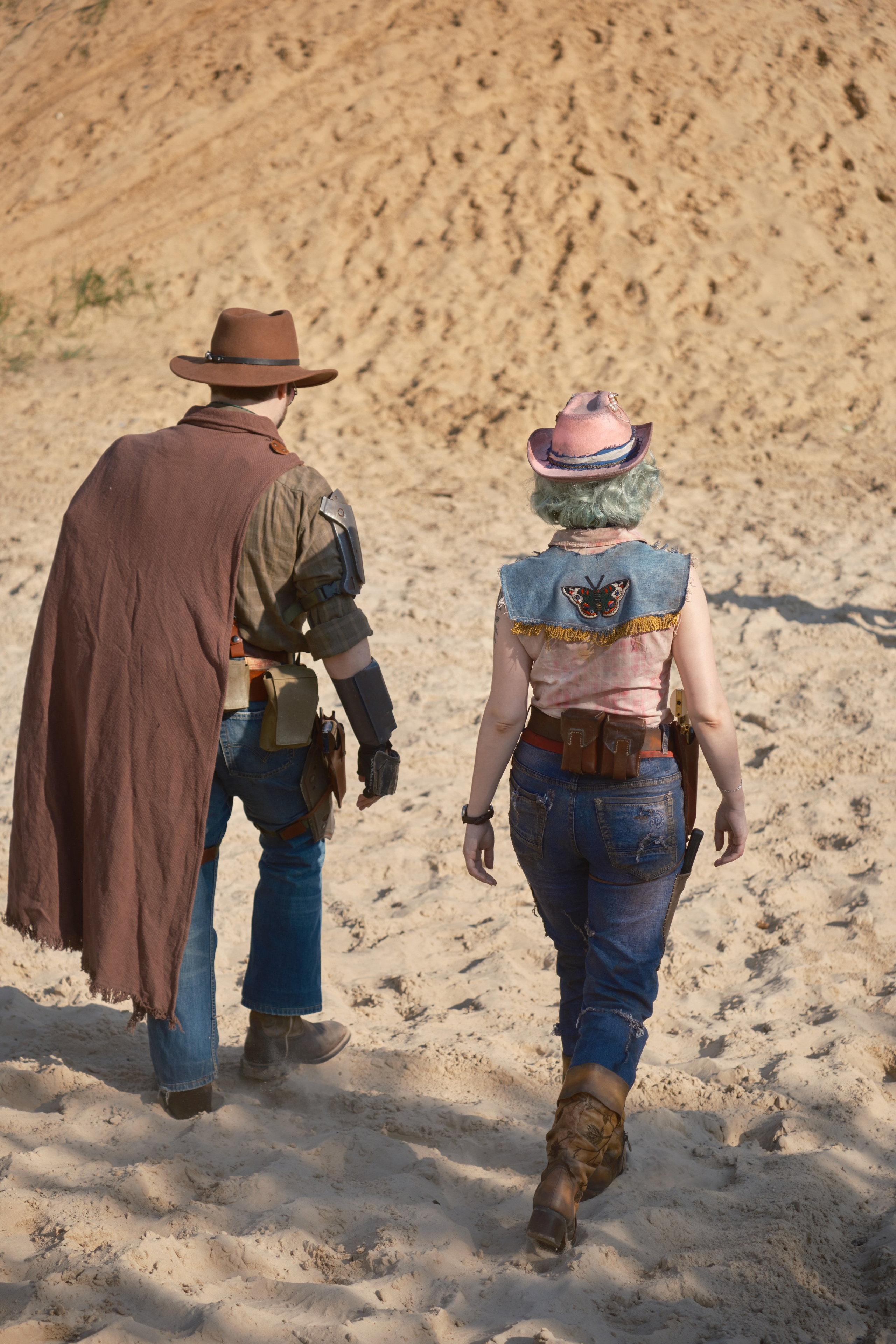 Мужчина и девушка в ковбойских шляпах уходят спиной
