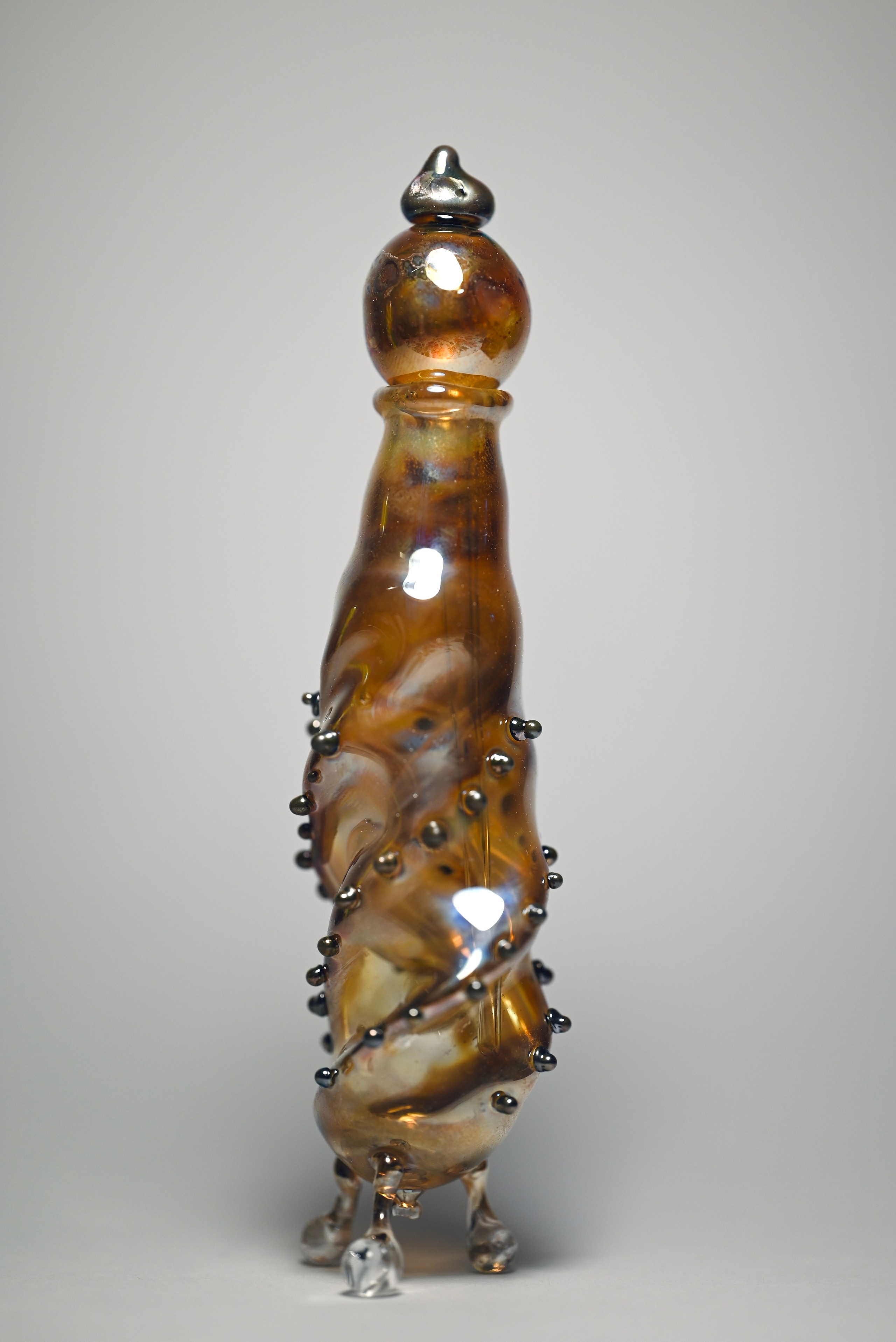 alt="Авторская стеклянная скульптура с прозрачной крышкой, янтарным корпусом и декоративными каплями на поверхности."
