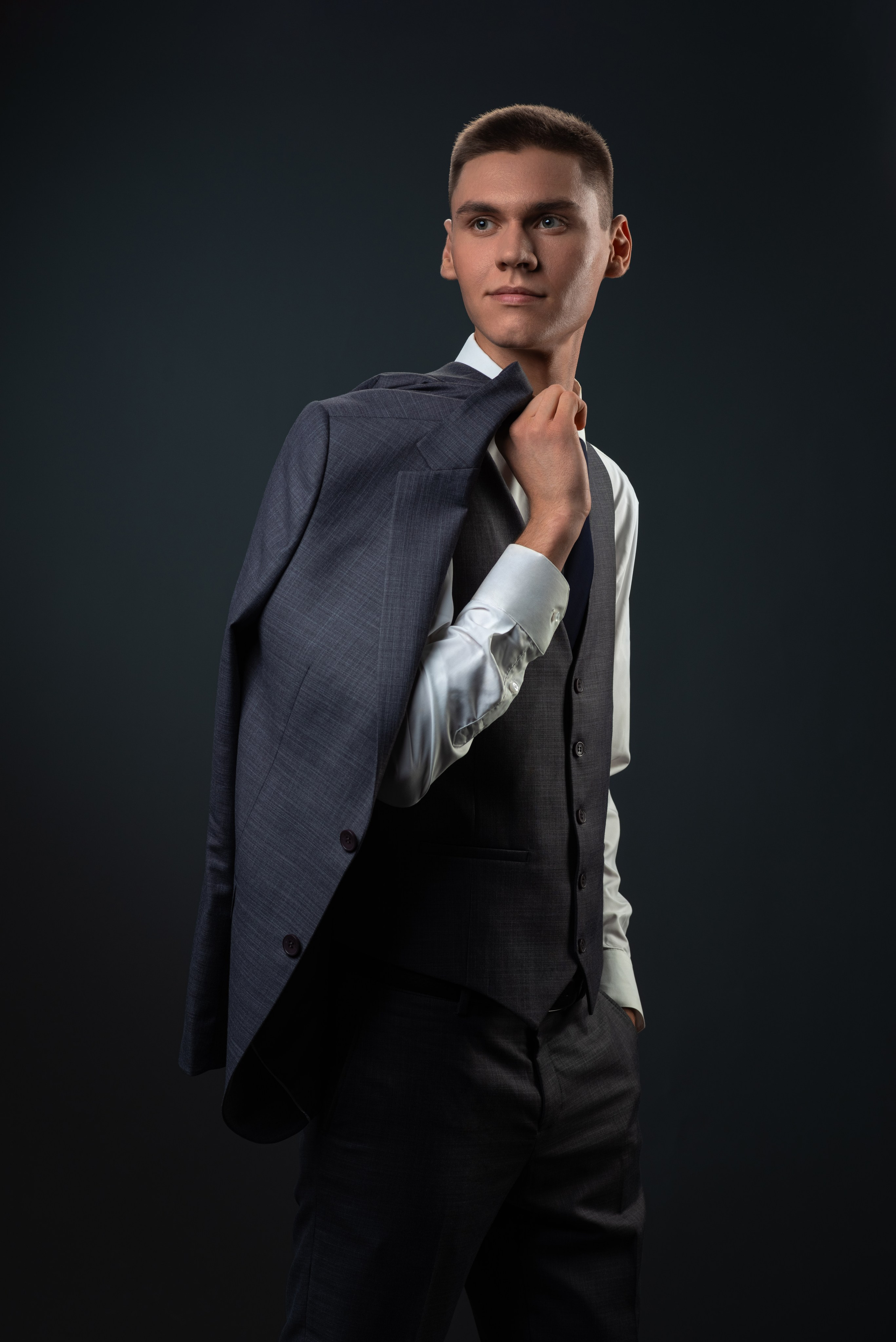 Портрет парня в белой рубашке и пиджаком на плече.