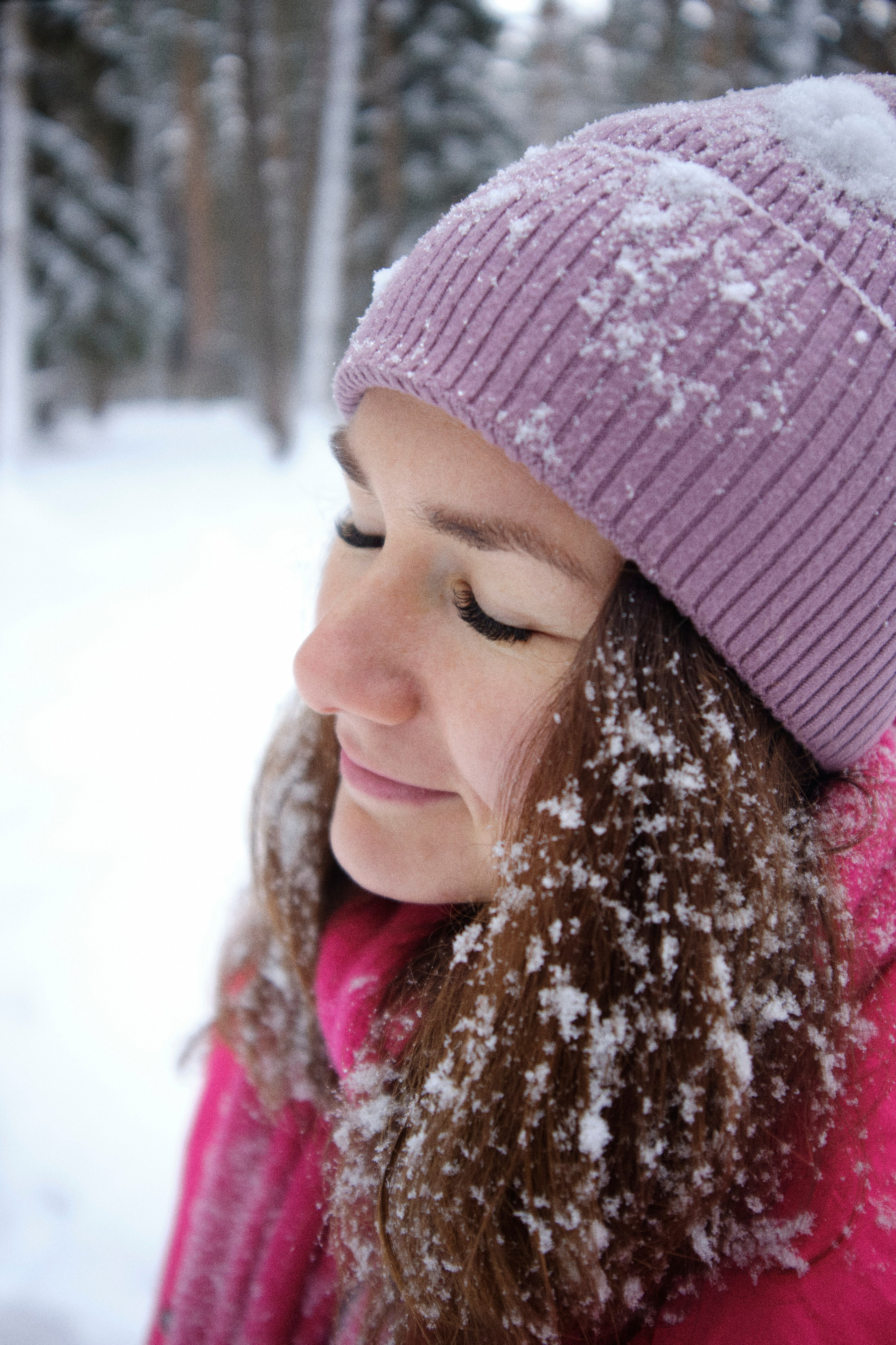 Девушка зимой в шапке, на волосах и одежде снежиники