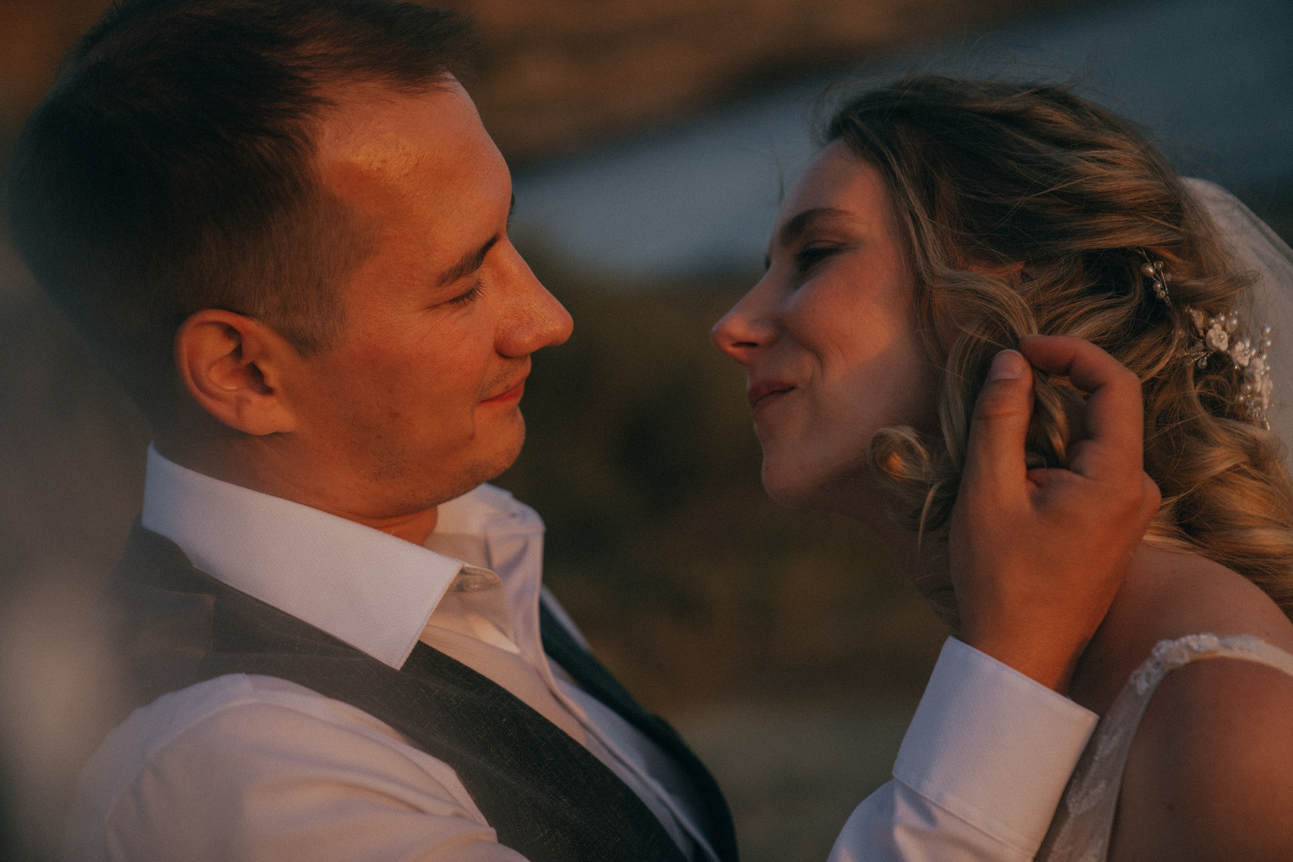 Счастливая пара жених и невеста целуется на фоне волн  скал и заката у моря океана.