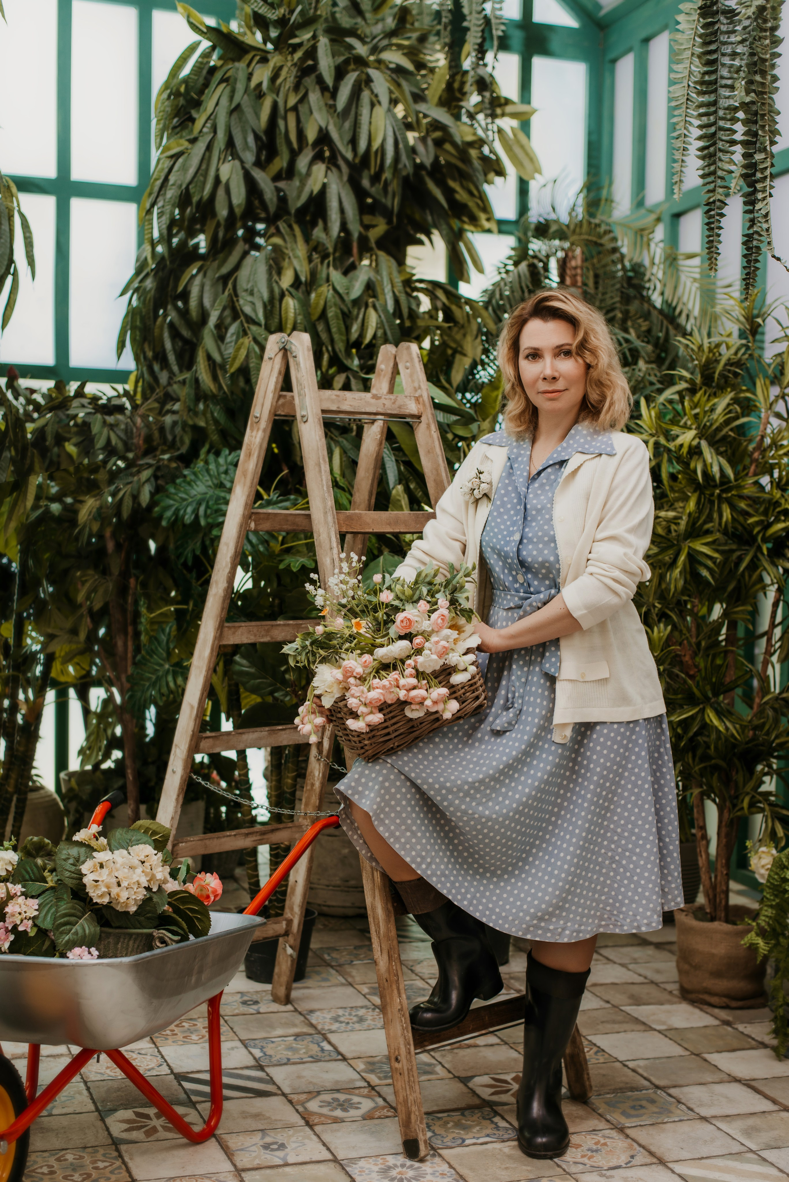 Фотосессия в цветущем саду женщины в голубом платье на фоне лестнице с корзиной цветов 