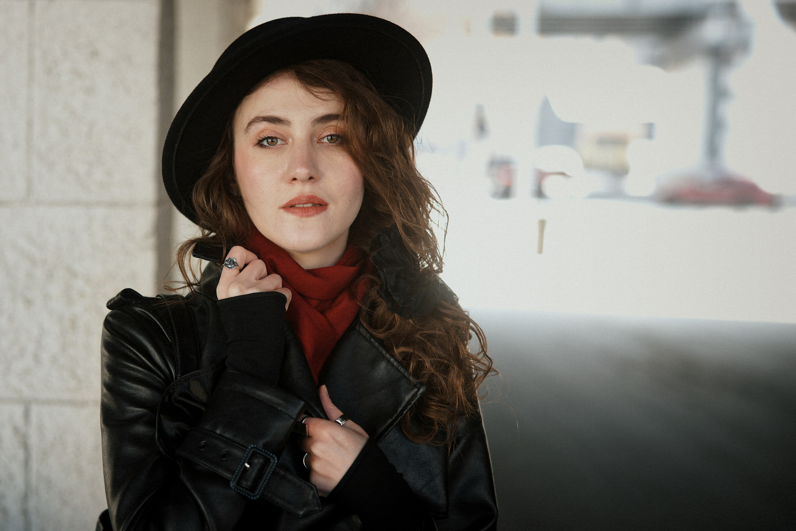 Крупный план портрета девушки в черной шляпе и красном шарфе, кожаная куртка, вьющиеся волосы, естественный макияж