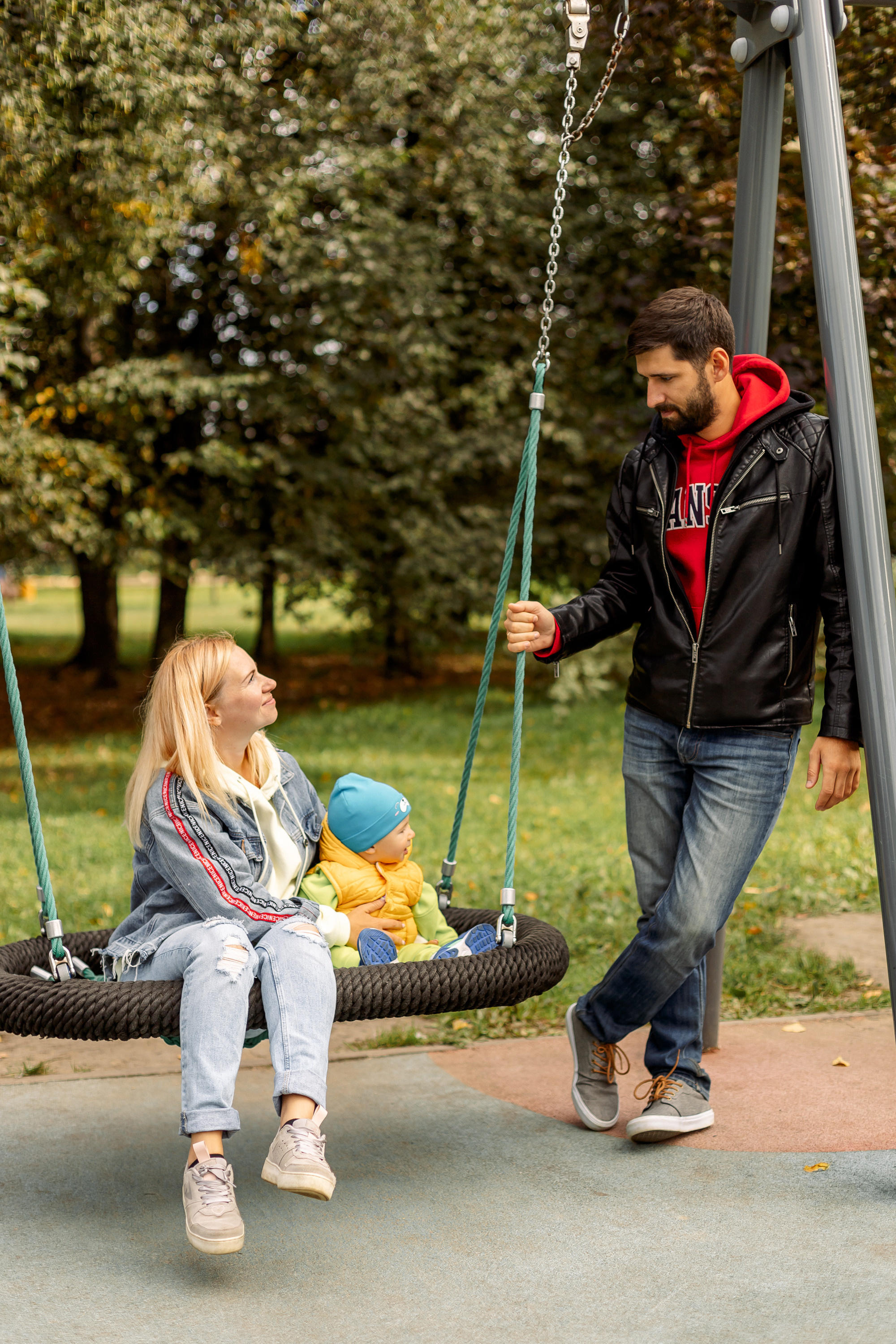 папа катает на качелях сына с мамой