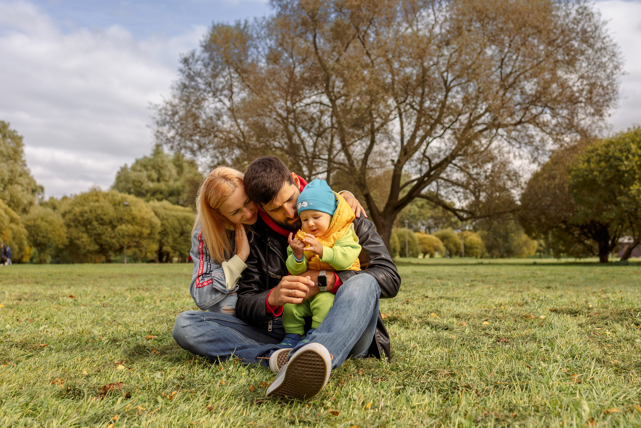 семья сидит на траве в парке