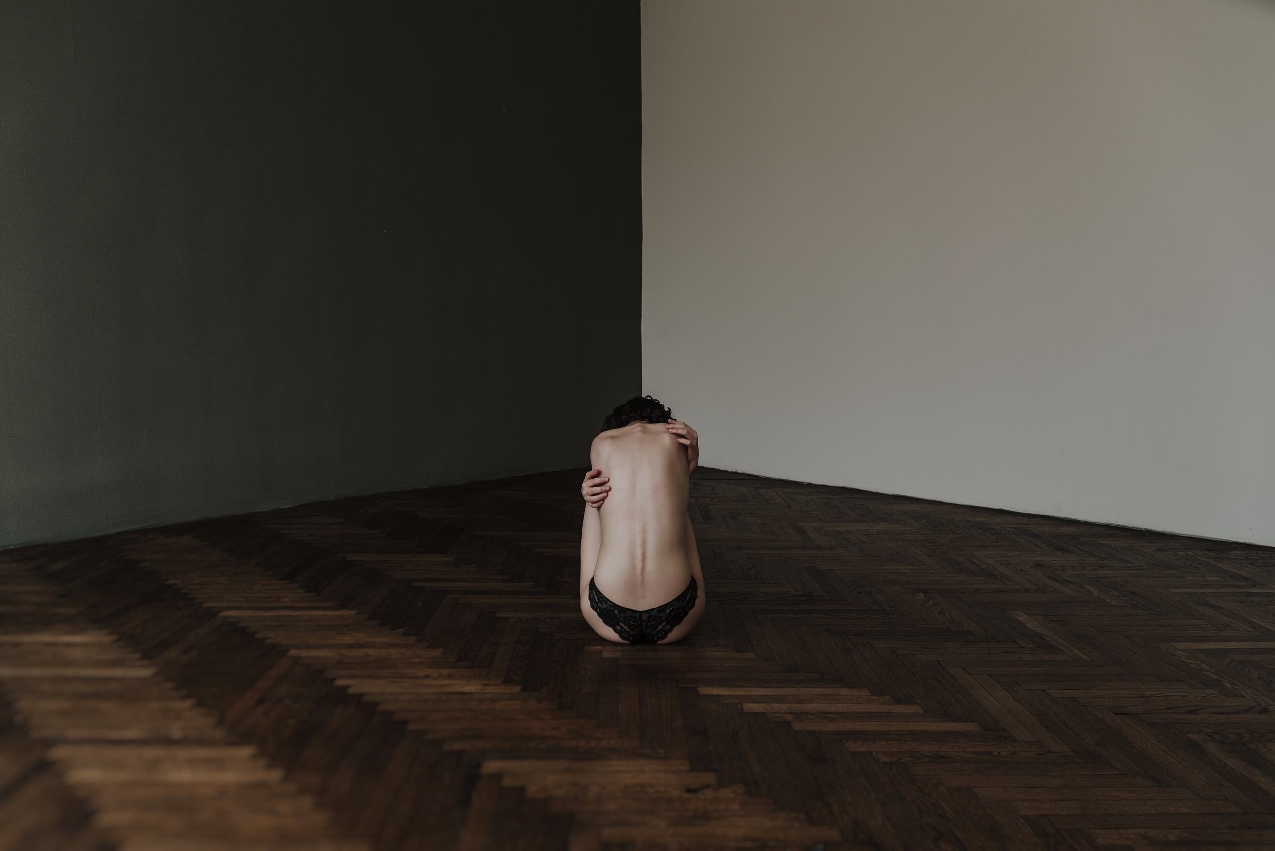 Девушка в одиночестве сидит посреди пустой комнаты.