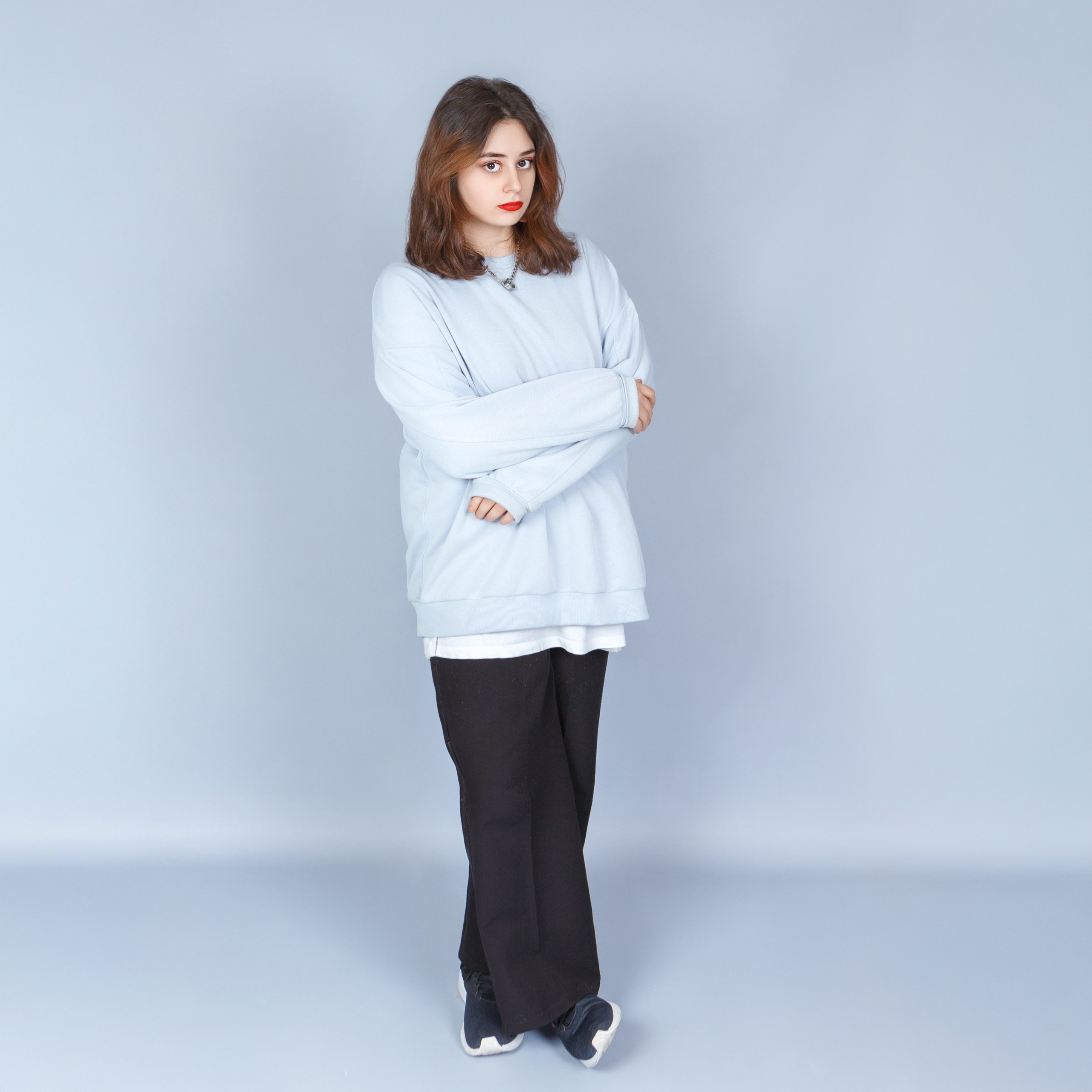 Девочка на светлом фоне в белом свитере, школьный портрет