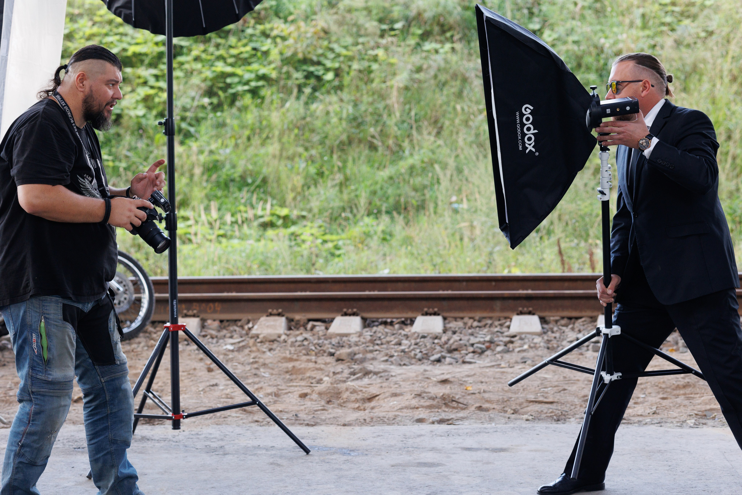 фотограф дает указания мужчине в строгом костюме с лайтбоксом стрипбоксом на съемках