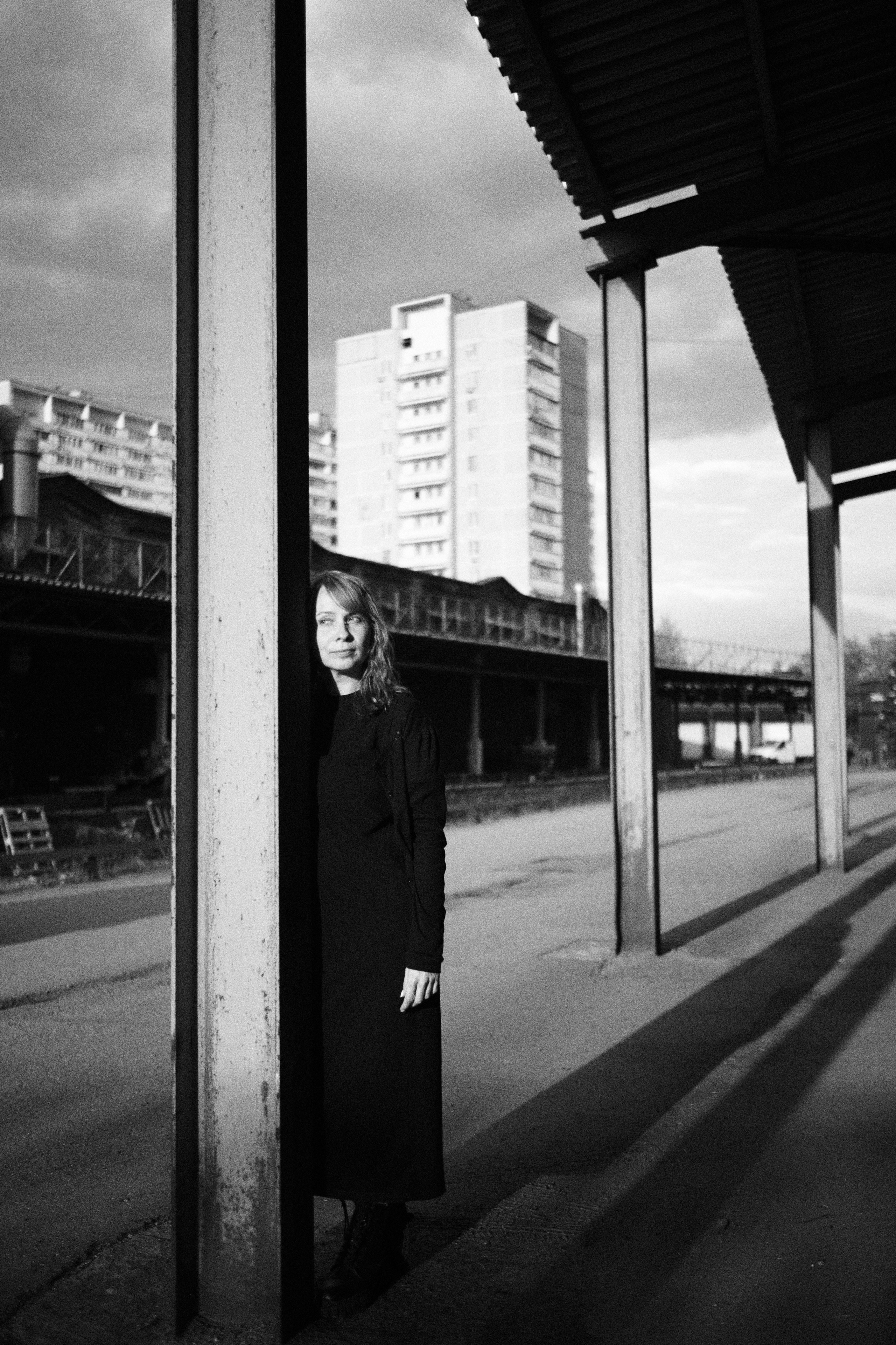 Женщина стоит, прислонившись к опоре