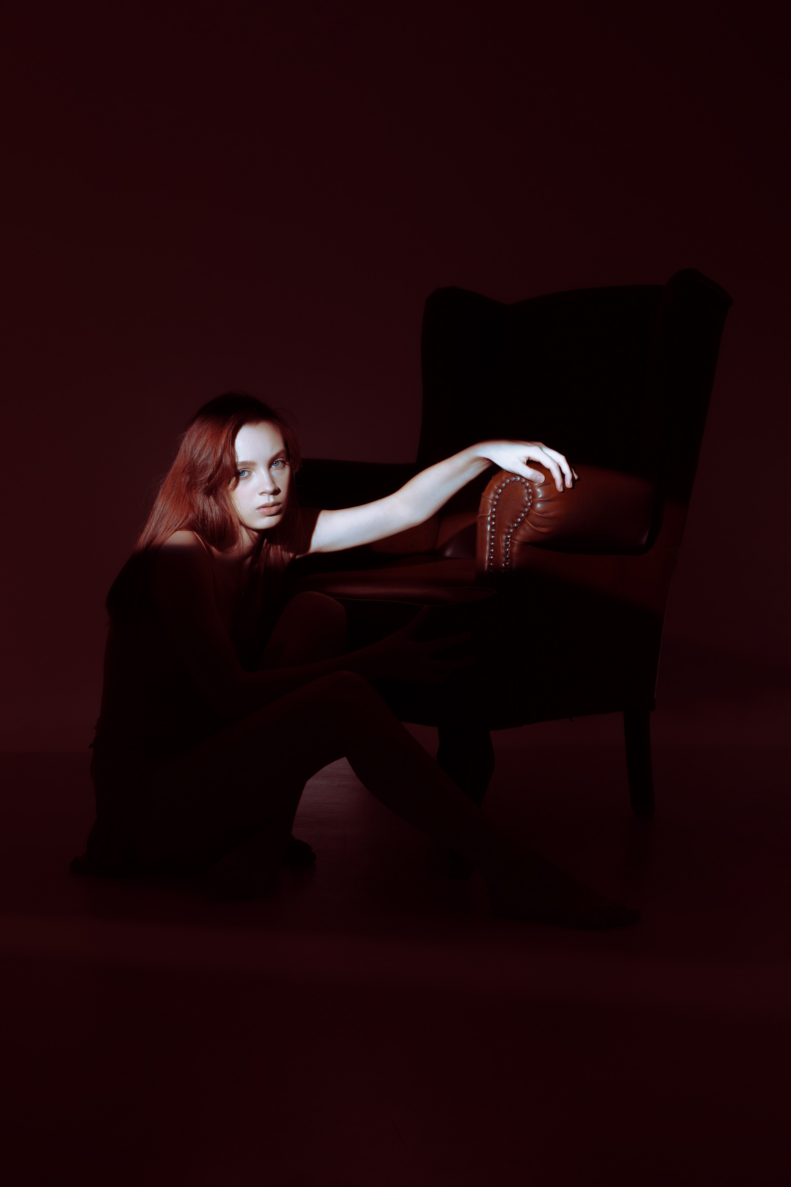 Минимализм в фотосъёмке: девушка в платье сидит в кресле, обрамлённая мягкими световыми акцентами. Простой, но выразительный кадр для ценителей эстетики.