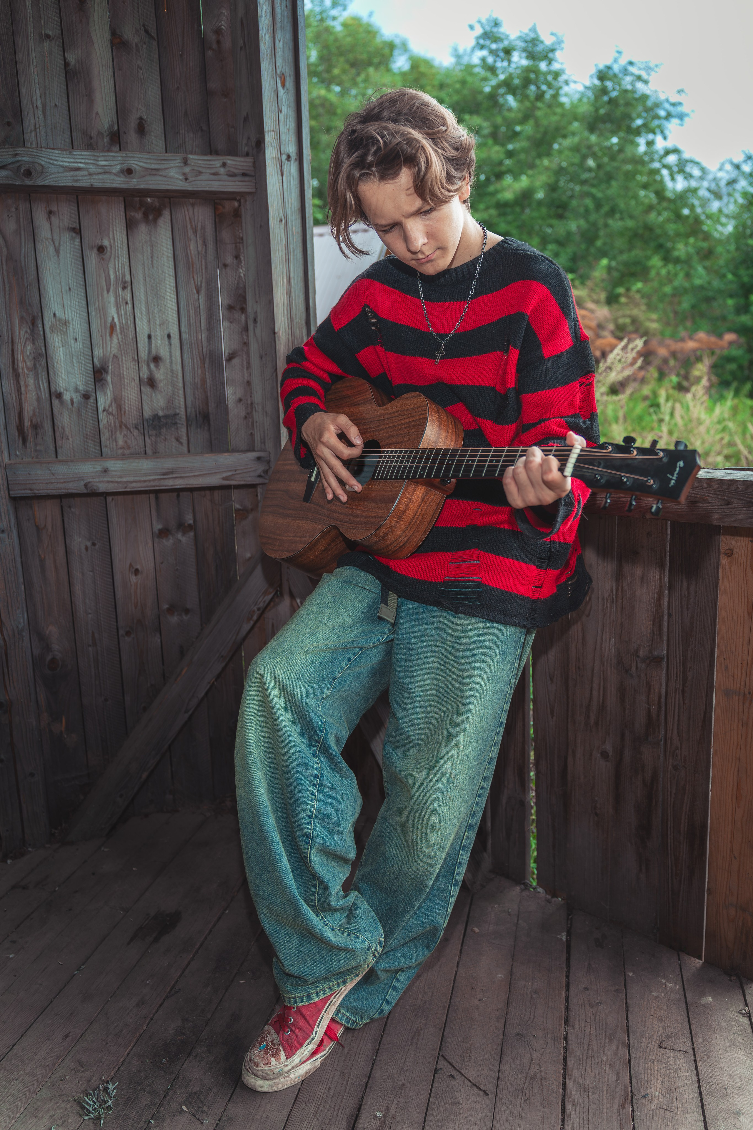 Молодой человек в стильной одежде играет на гитаре