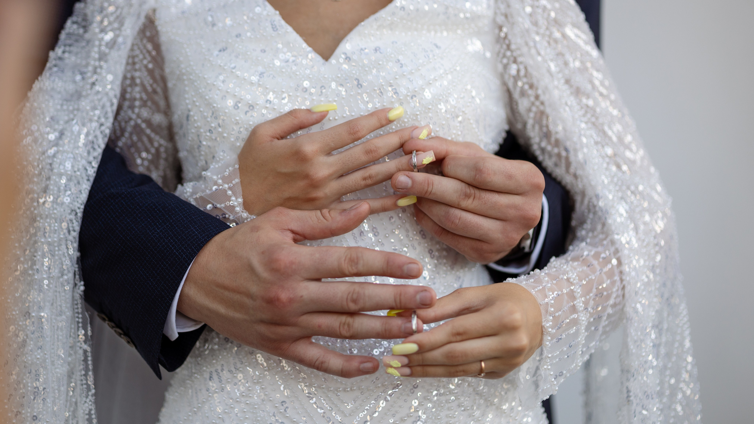 На переднем фоне руки молодых с обручальными кольцами.