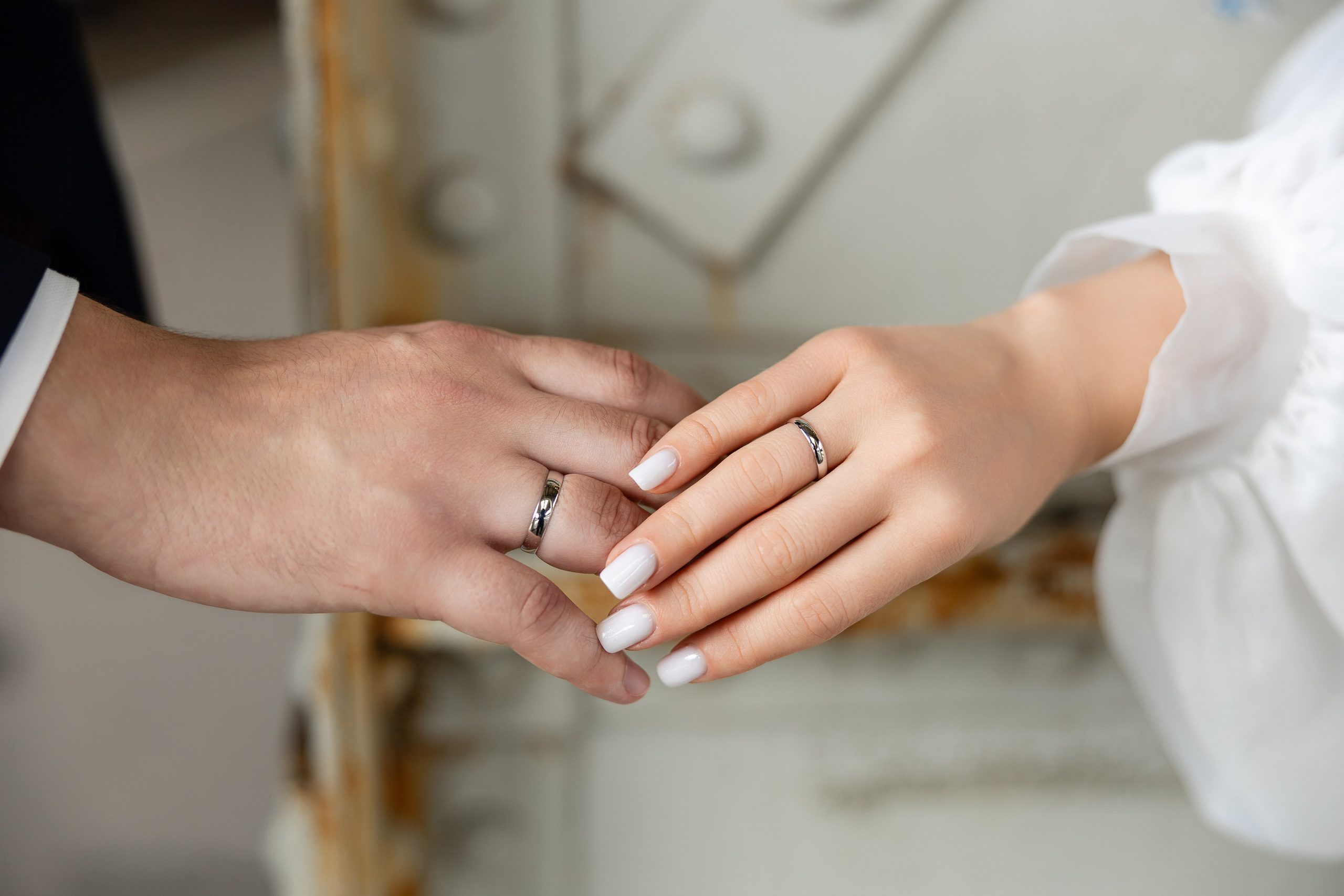 Руки молодожен с обручальными кольцами, надетыми на безымянные пальцы