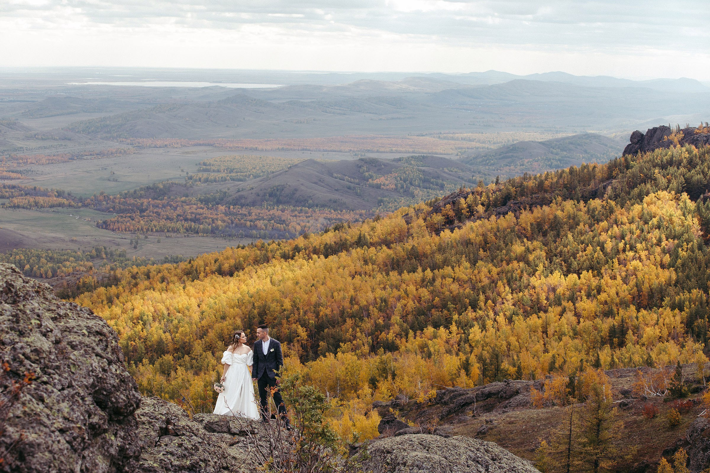 Свадебная пара позирует на фоне горного ущелья на озере Банное 
