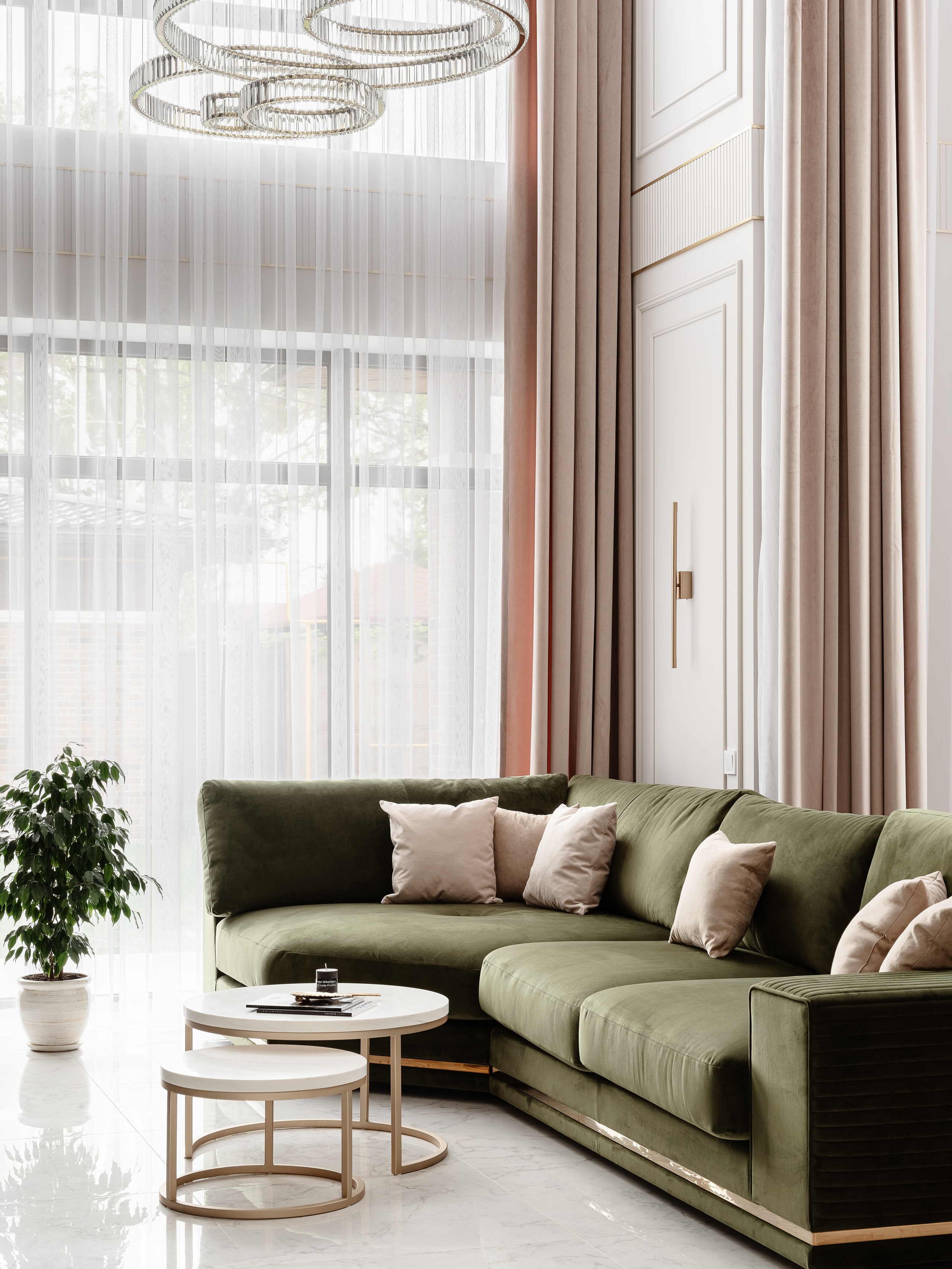 Современная гостиная с зеленым диваном, бежевыми подушками и белыми столиками на фоне высоких окон со светлыми шторами, интерьер в спокойной цветовой гамме, дизайнер Евгения Ермошина, фото Сергея Денисенко.