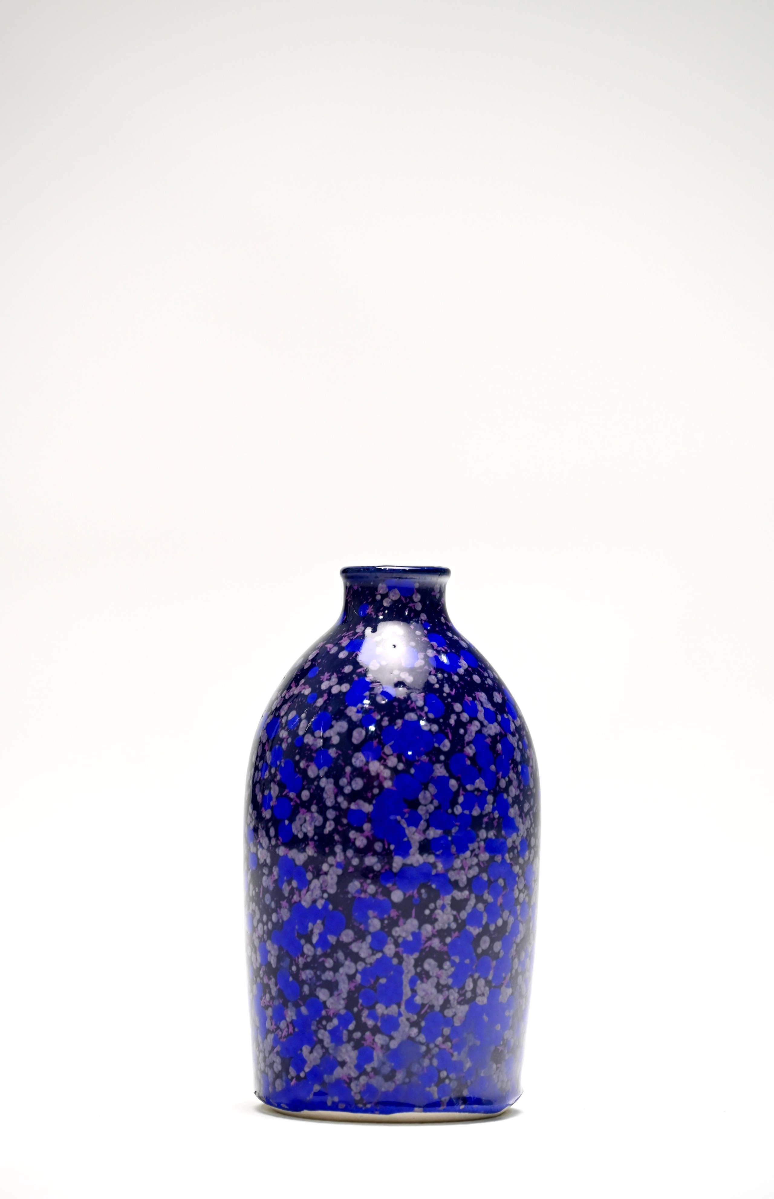 «Эфир». Каменная масса, кристаллическая глазурь. 15х8 см, 2025. Сосуд «Эфир» воплощает идею первичной стихии, в которой рождается движение и жизнь. Его поверхность покрыта холодными синими и серебристыми кристаллами, словно застывшими в момент испарения. Глубокий кобальтовый фон и переливчатая структура глазури создают впечатление эфемерности и вечного движения, будто материя вот-вот рассеется в воздухе и снова соберётся в новые формы. 