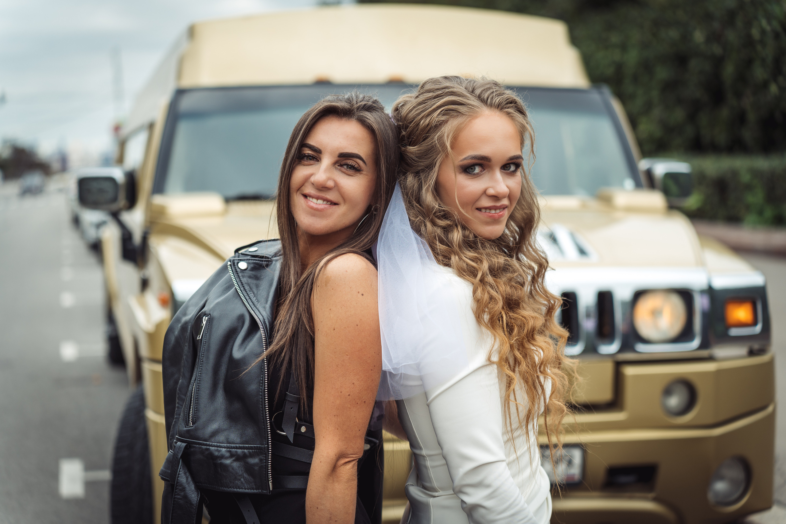 На фоне лимузина в Москве на Воробьевых горах невеста с подружкой позируют для фотографа