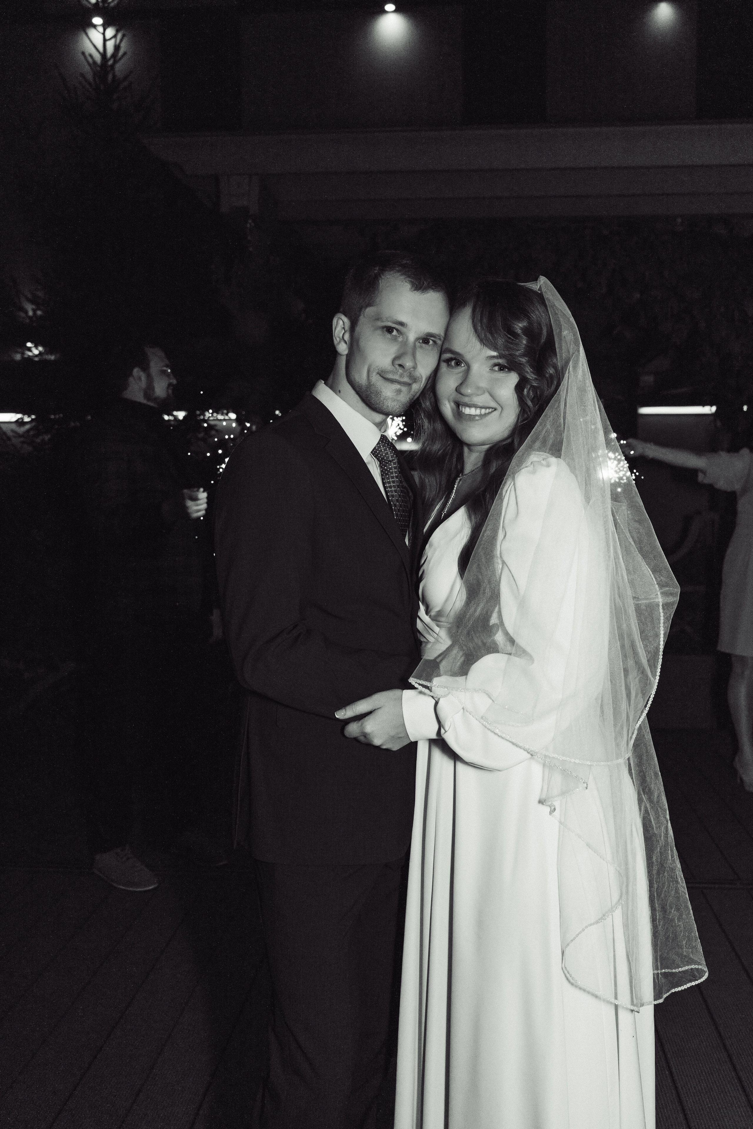 Невеста и жених на фоне коридора из бенгальских огней целуются 