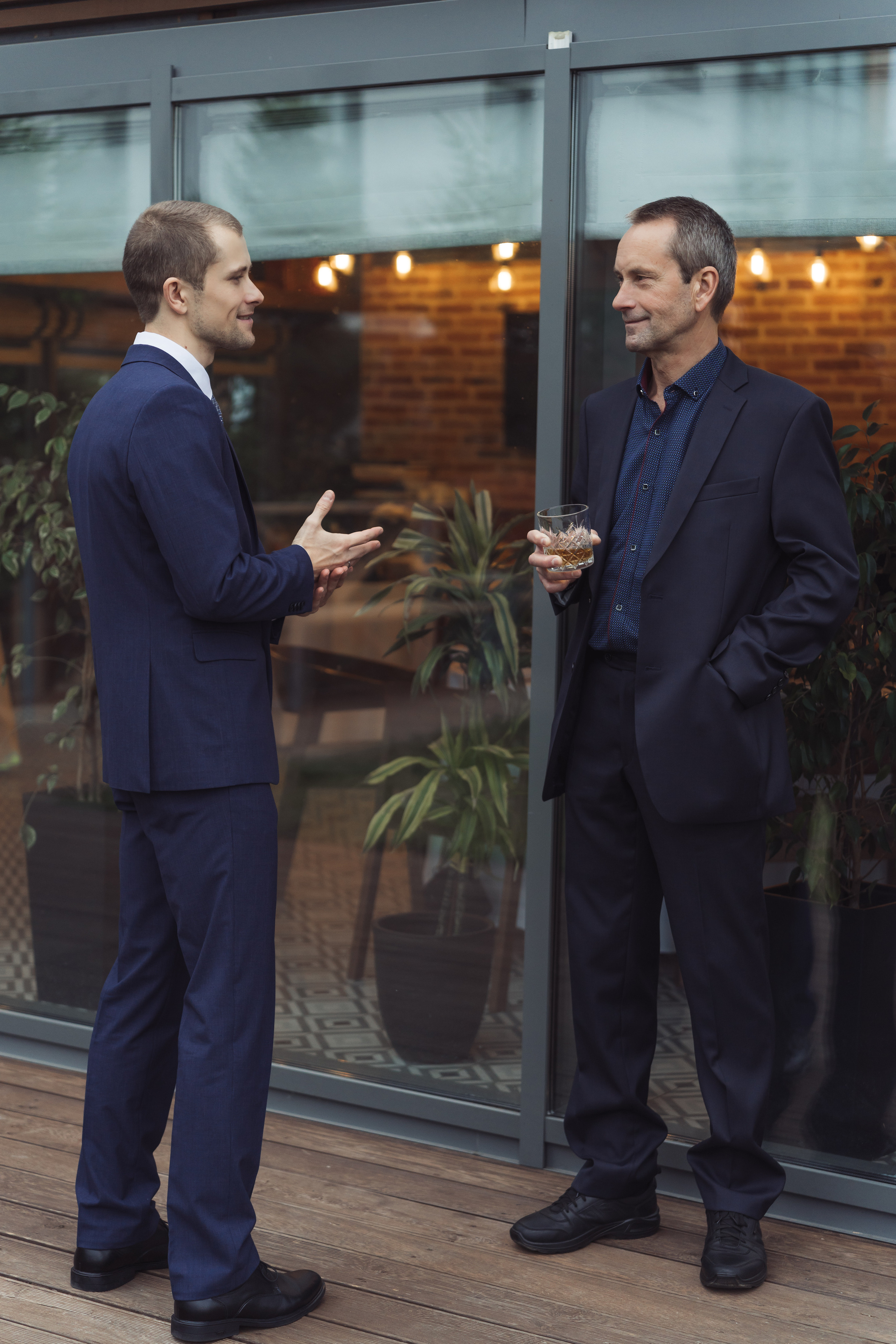 Папа с сыном женихом в костюмах обсуждают свадьбу