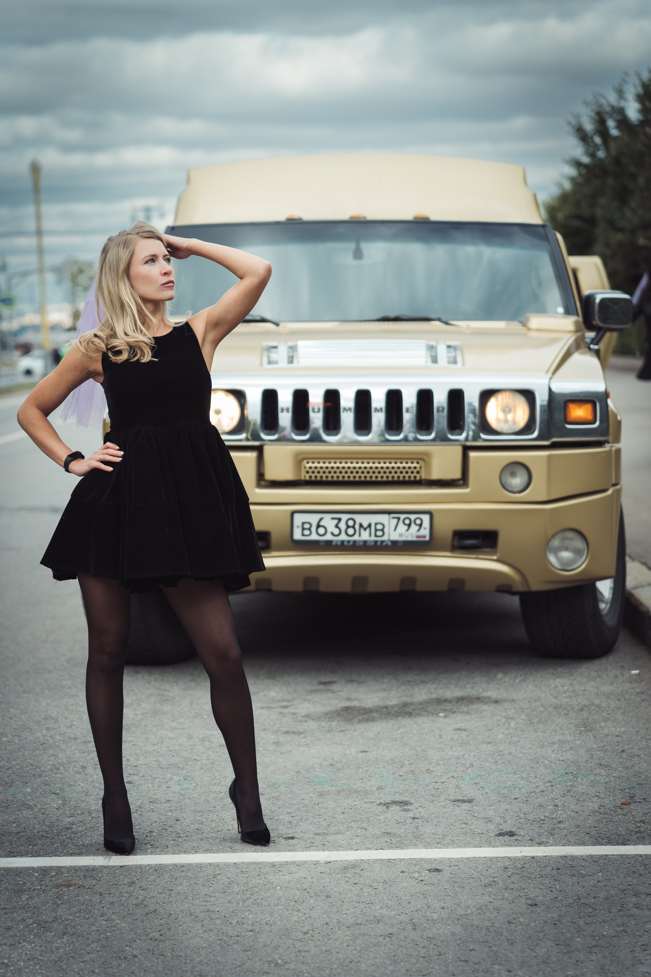 Девушка в черном мини платье на фоне машины 