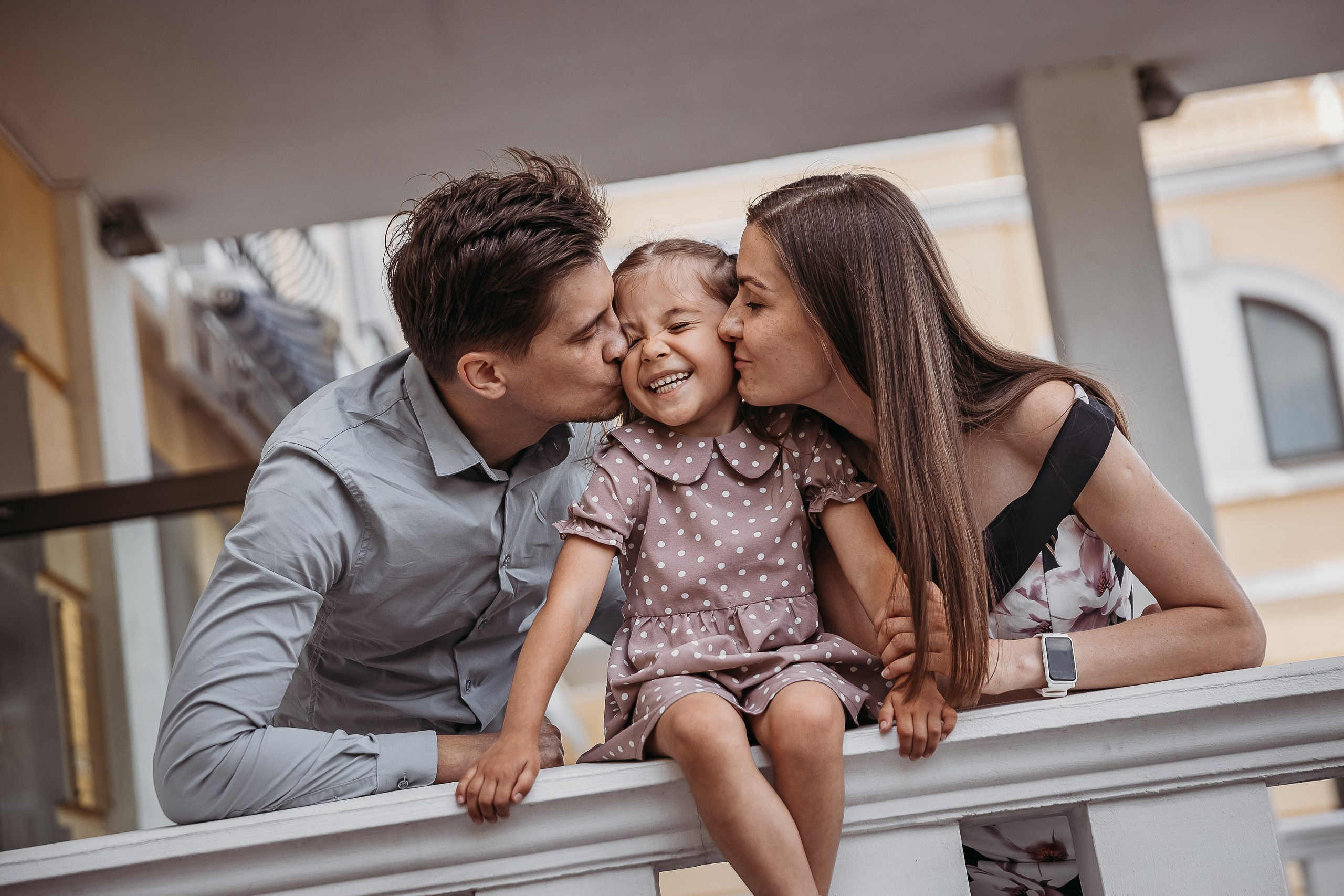 мама и папа целуют в щеки дочку а она смеётся