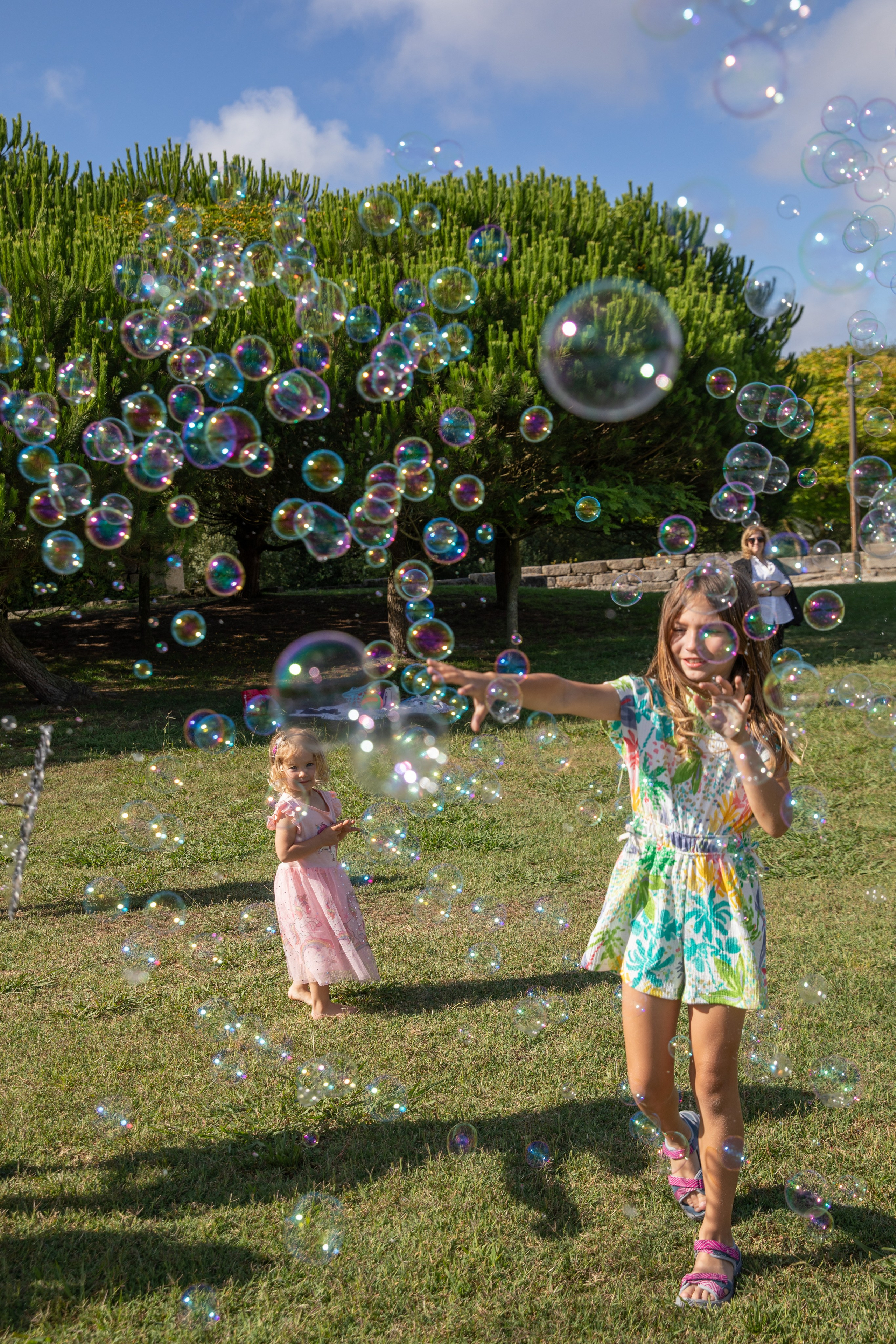 Smiling kids playing and blowing soap bubbles at a birthday photo shoot in the park