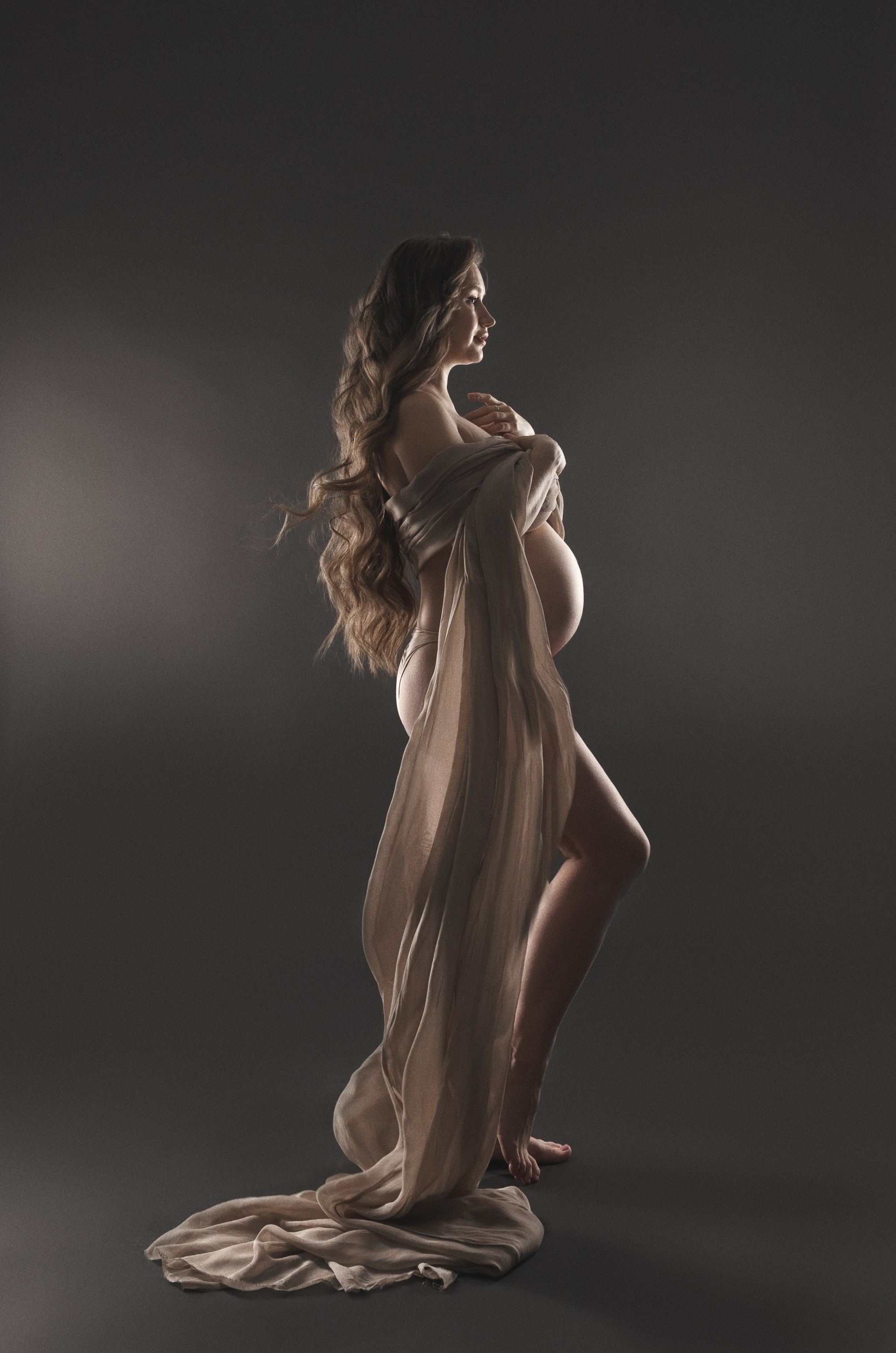 фотосессия беременной в фотостудии на темном фоне в красивом разлетающемся платье, фотография беременности, фотосессия беременных, портрет беременной