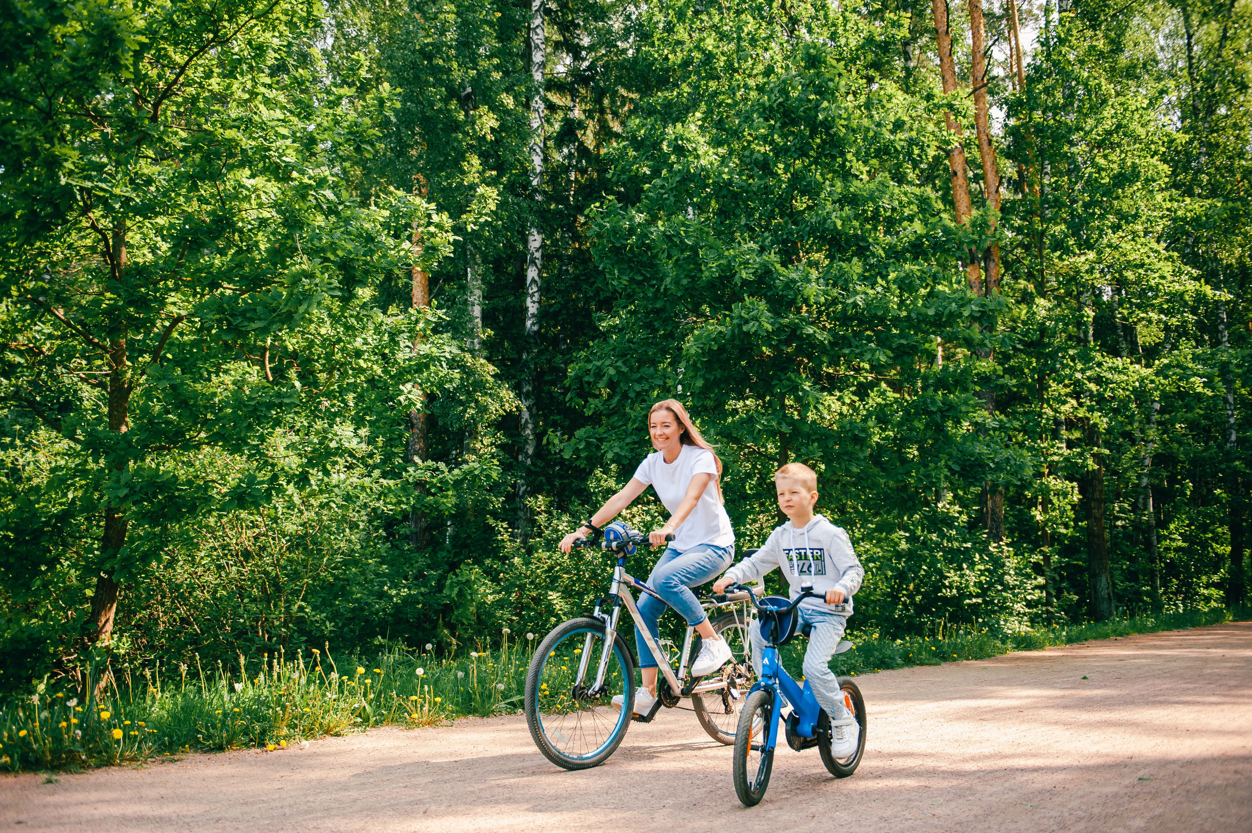 мама с сыном катаются на велосипедах в парке
