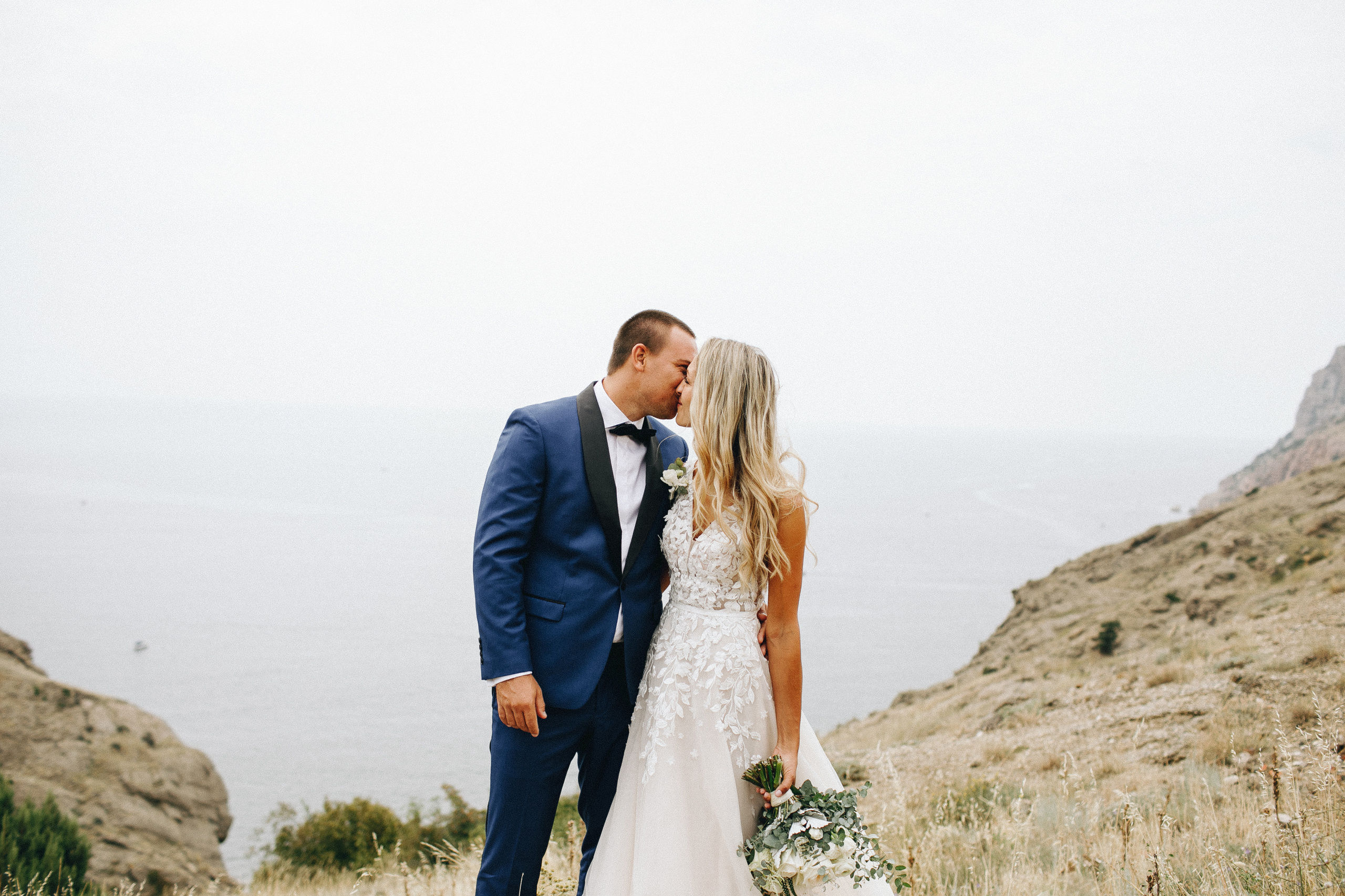 Нежный поцелую жениха и невесты во время прогулки по живописным горам в Крыму.