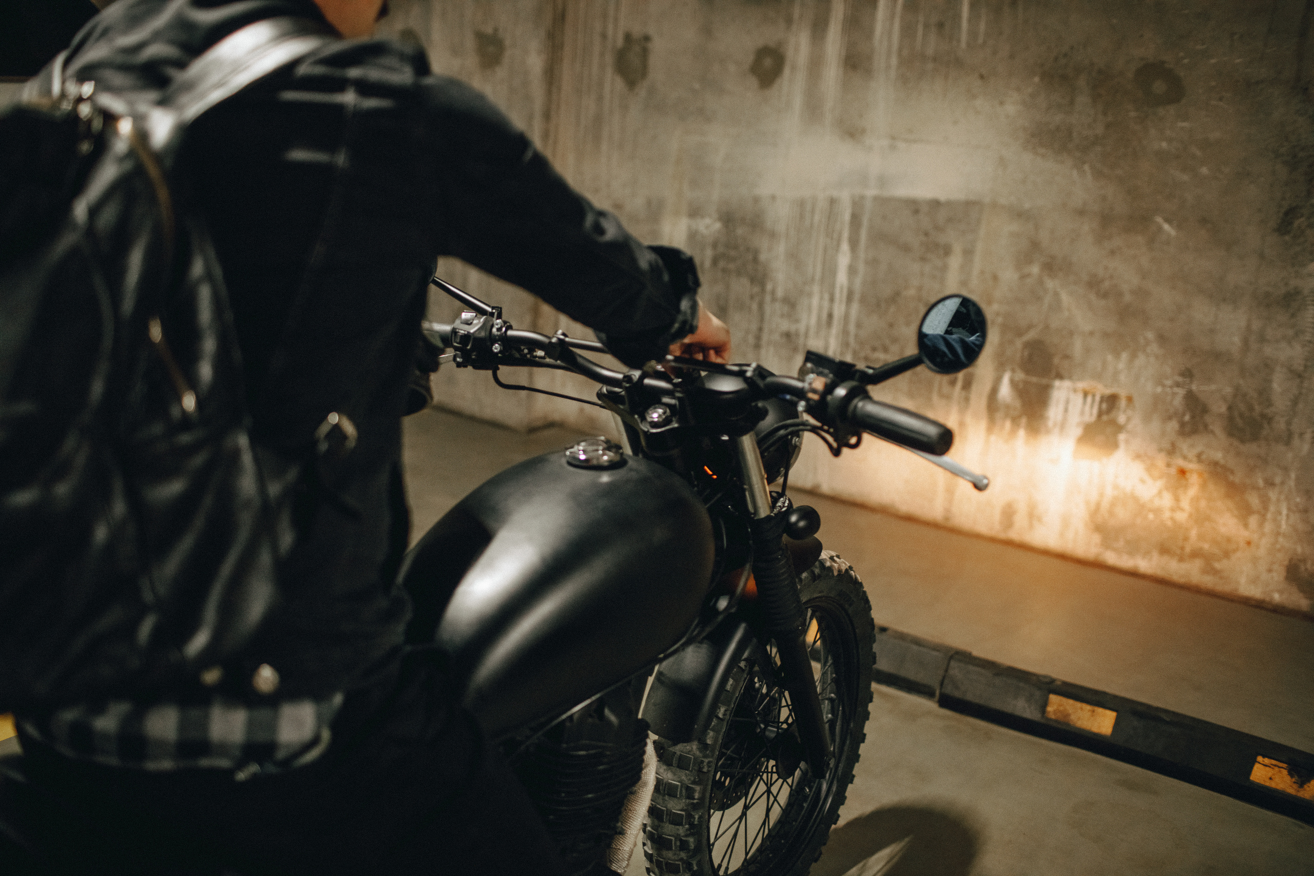 Фонарь мотоцикла светил теплым жёлтым светом на стену парковки.