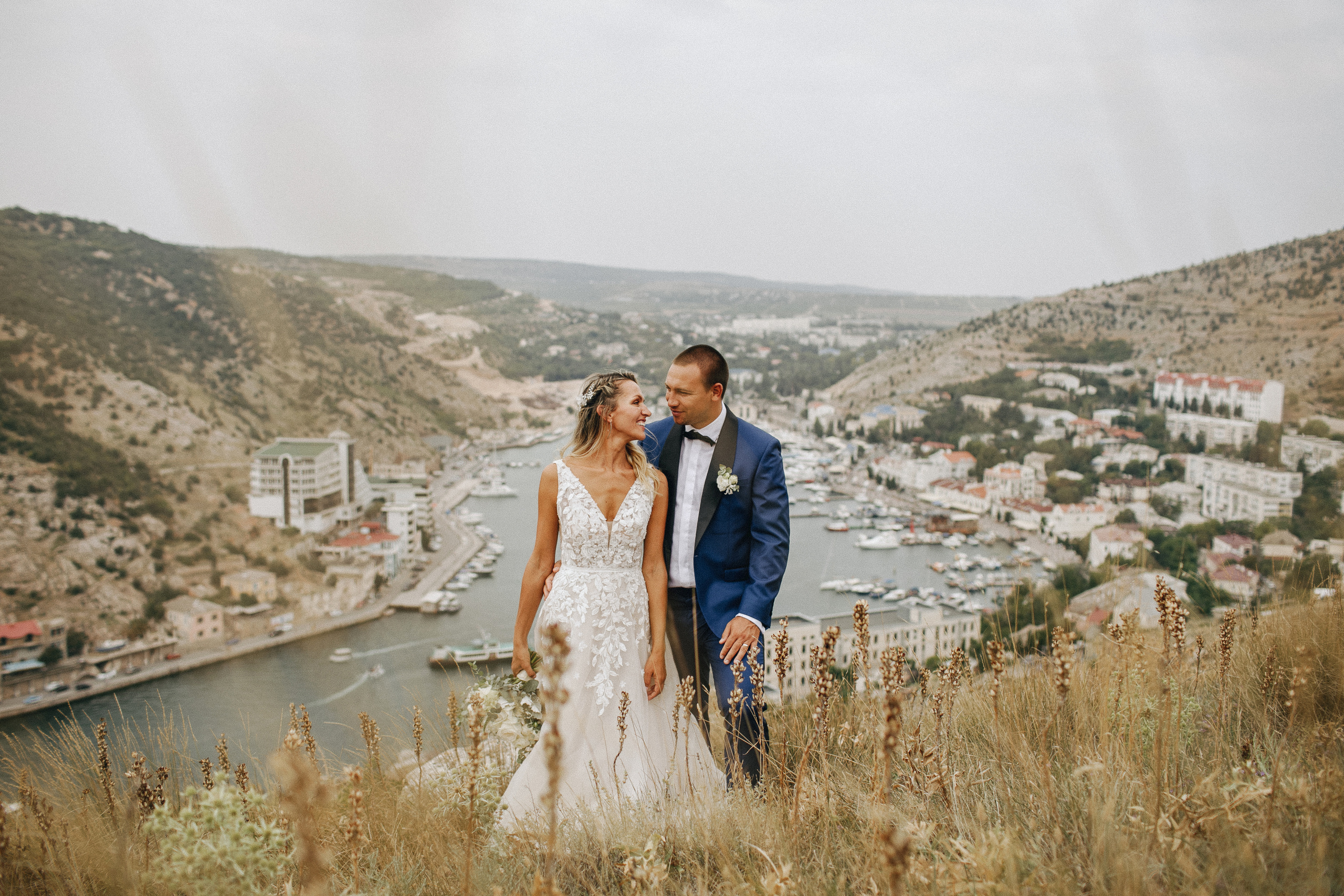 Красивый вид на Крымскую бухту Балаклава, жених смотрит на невесту и обнимая ее за талию. 