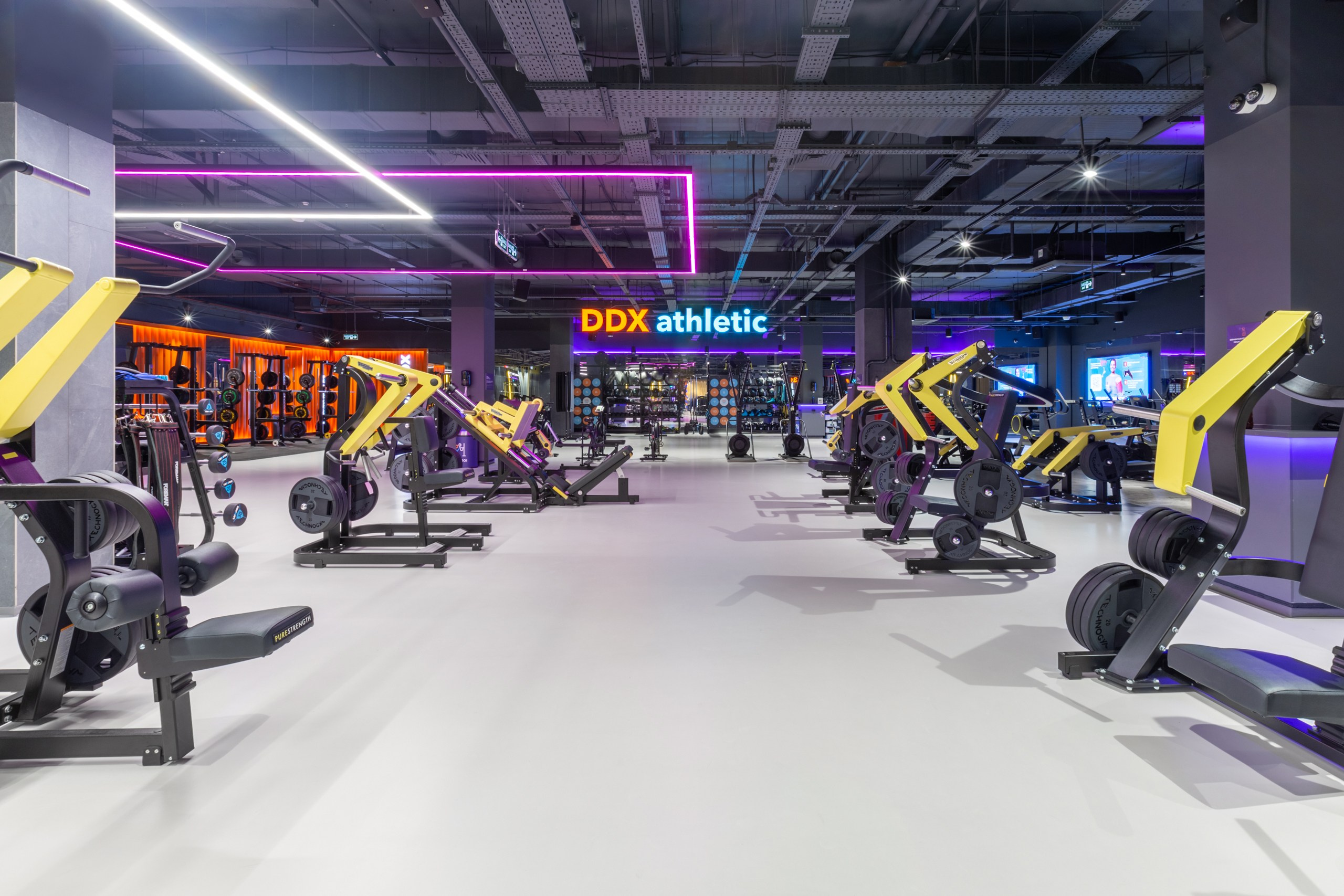 Тренажёры в дорогом фитнес центре. Фитнес зал DDX. Неоновый потолок в тренажёрном зале.