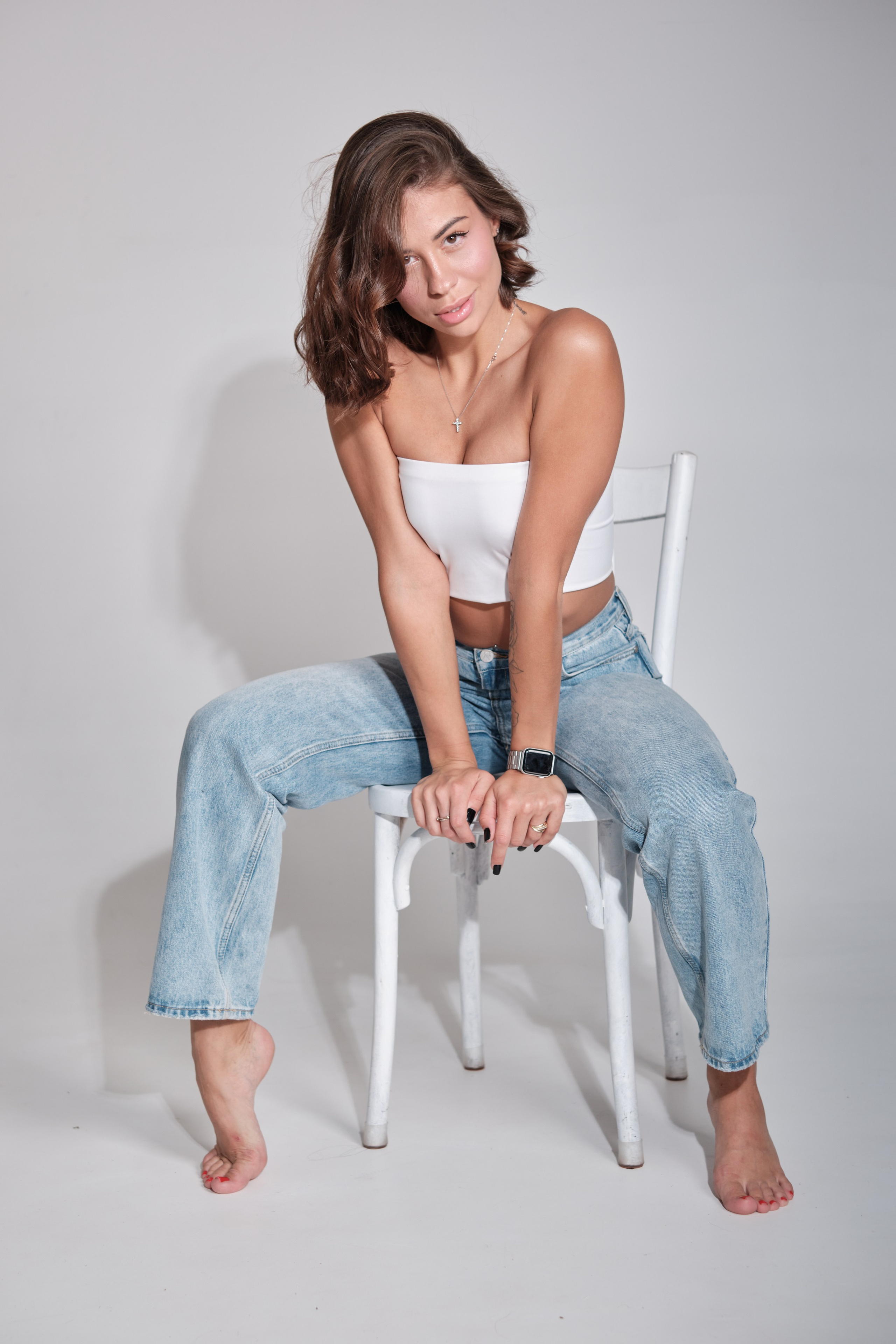 Сьемка в студии для модельного агентства, девушка в джинсах и белом топе на стуле