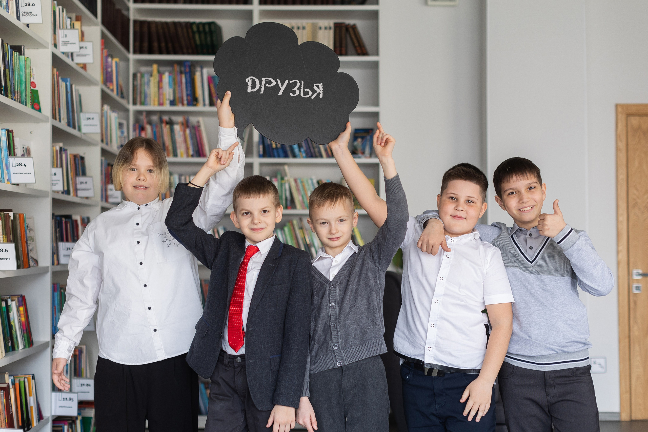 Группа мальчиков-друзей улыбаются и фотографируются в библиотеке.