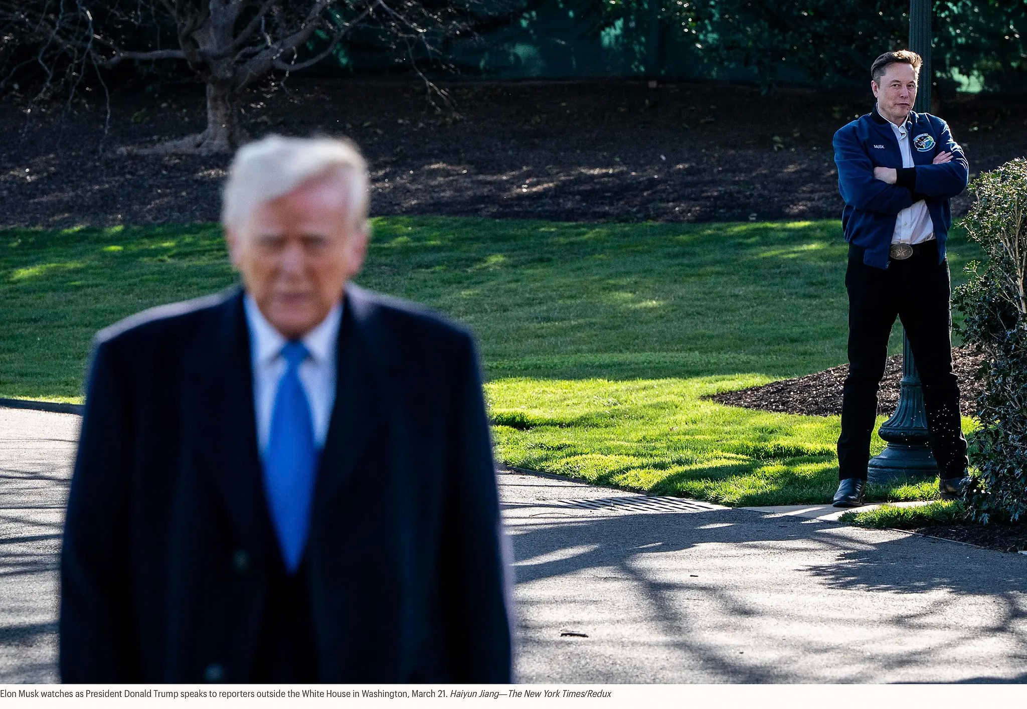 Илон Маск наблюдает за тем, как президент Дональд Трамп общается с журналистами у Белого дома в Вашингтоне, 21 марта. Хайюнь Цзян — The New York Times/Redux