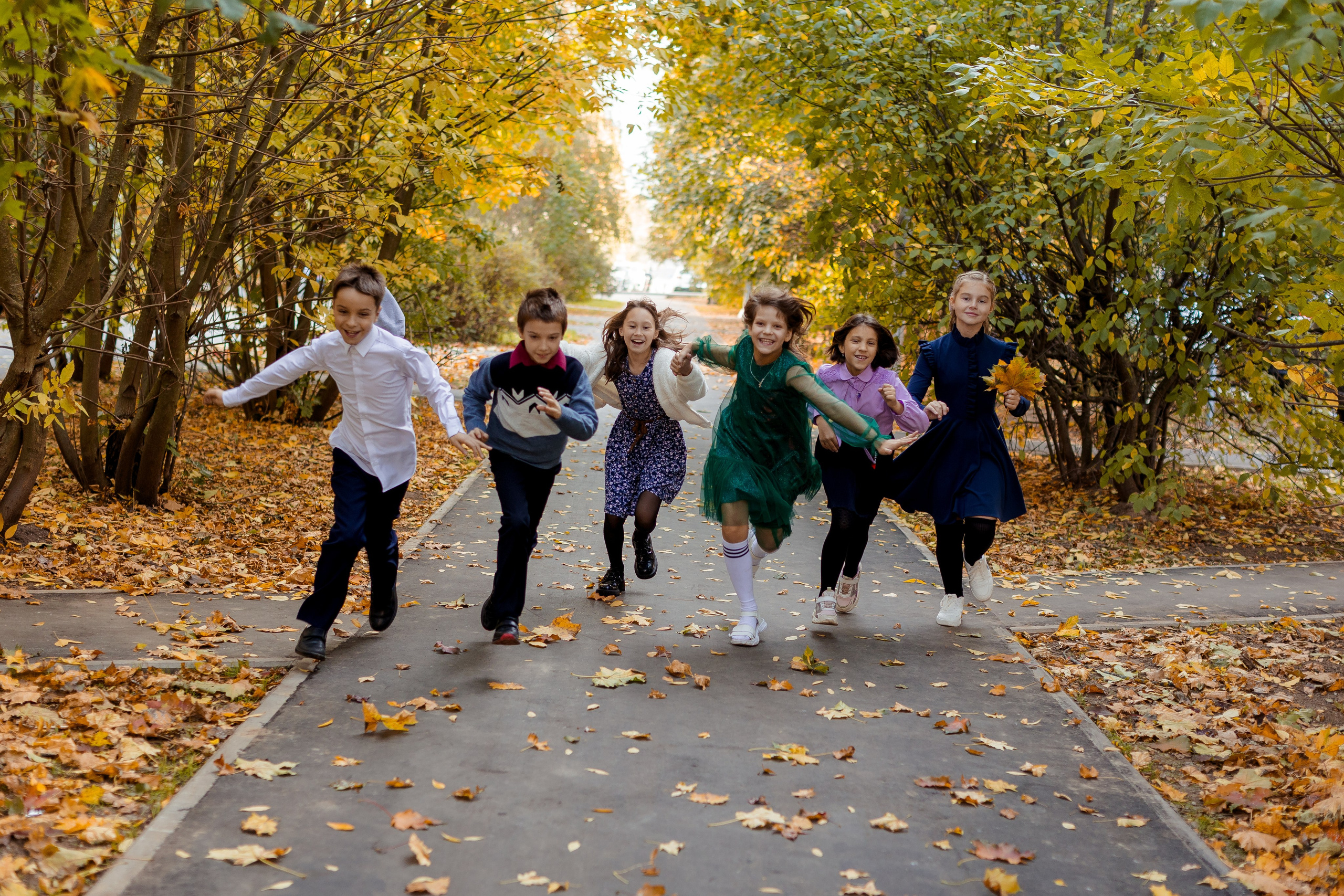 Девочки и мальчики весело бегут в осеннем парке
