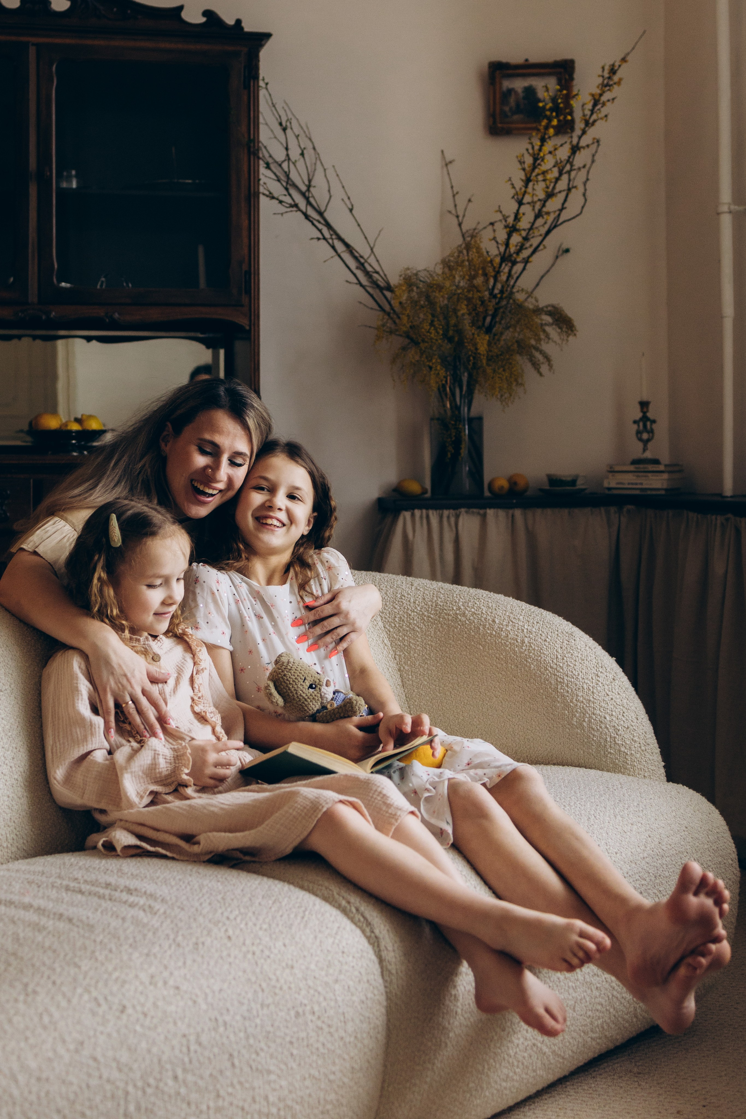 мама с дочками сидят вместе на диване и мило общаются