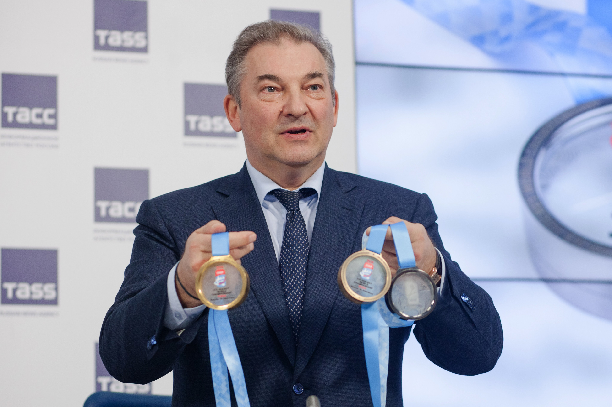 Мужчина держит медали за победу в чемпионате по футболу в руках