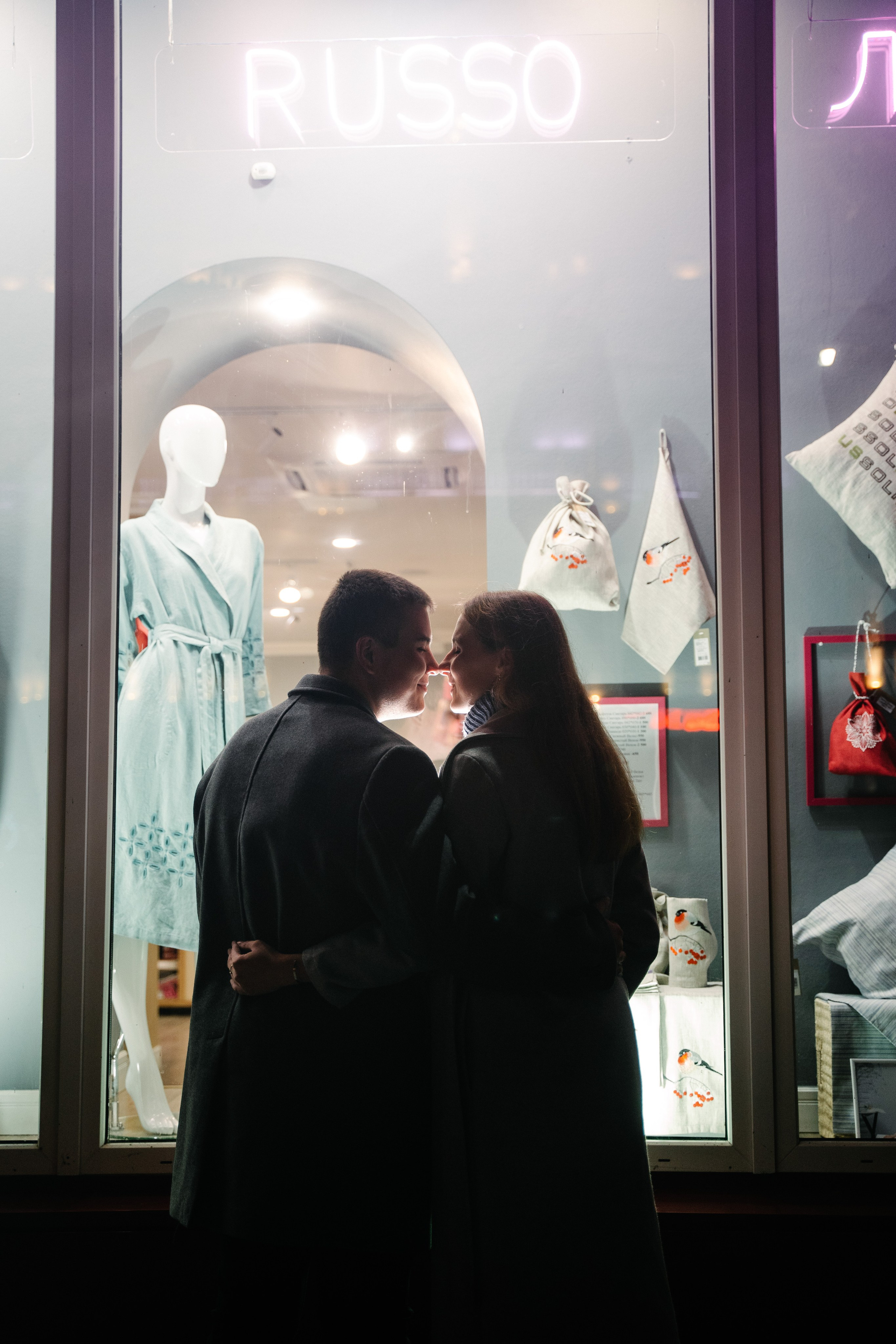 парень с девушкой стоят на фоне витрины в тени
