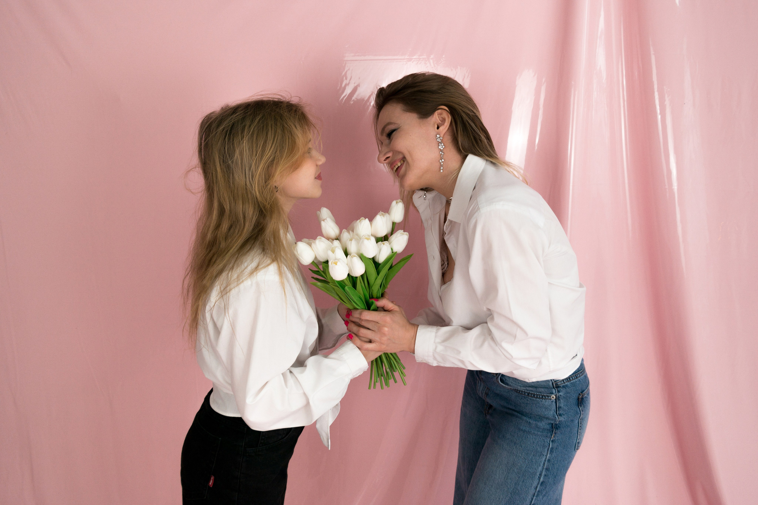 Семейная фотосессия в студии в Краснодаре. Мама с дочкой держат букет цветов на розовом фоне