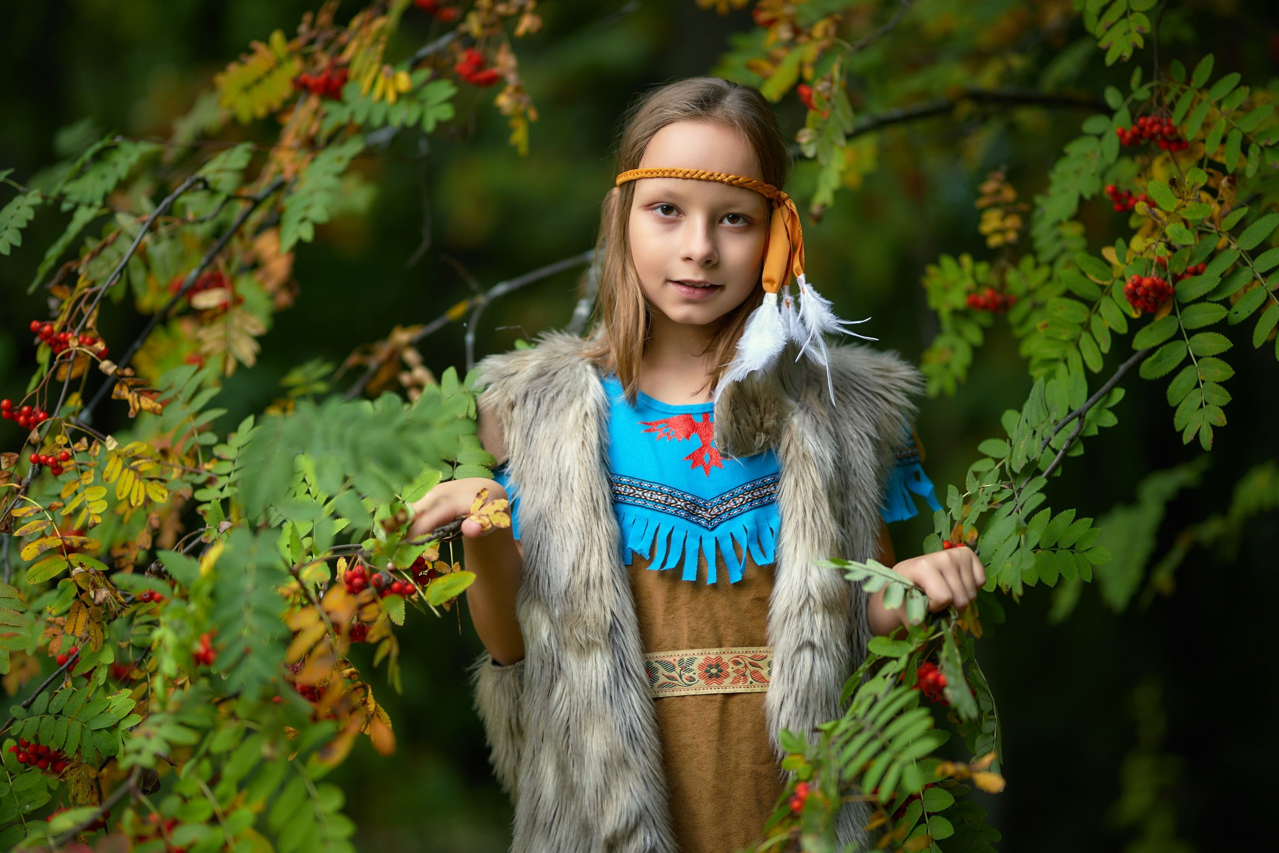 Девочка индианка стоит на фоне рябины в лакреевском парке