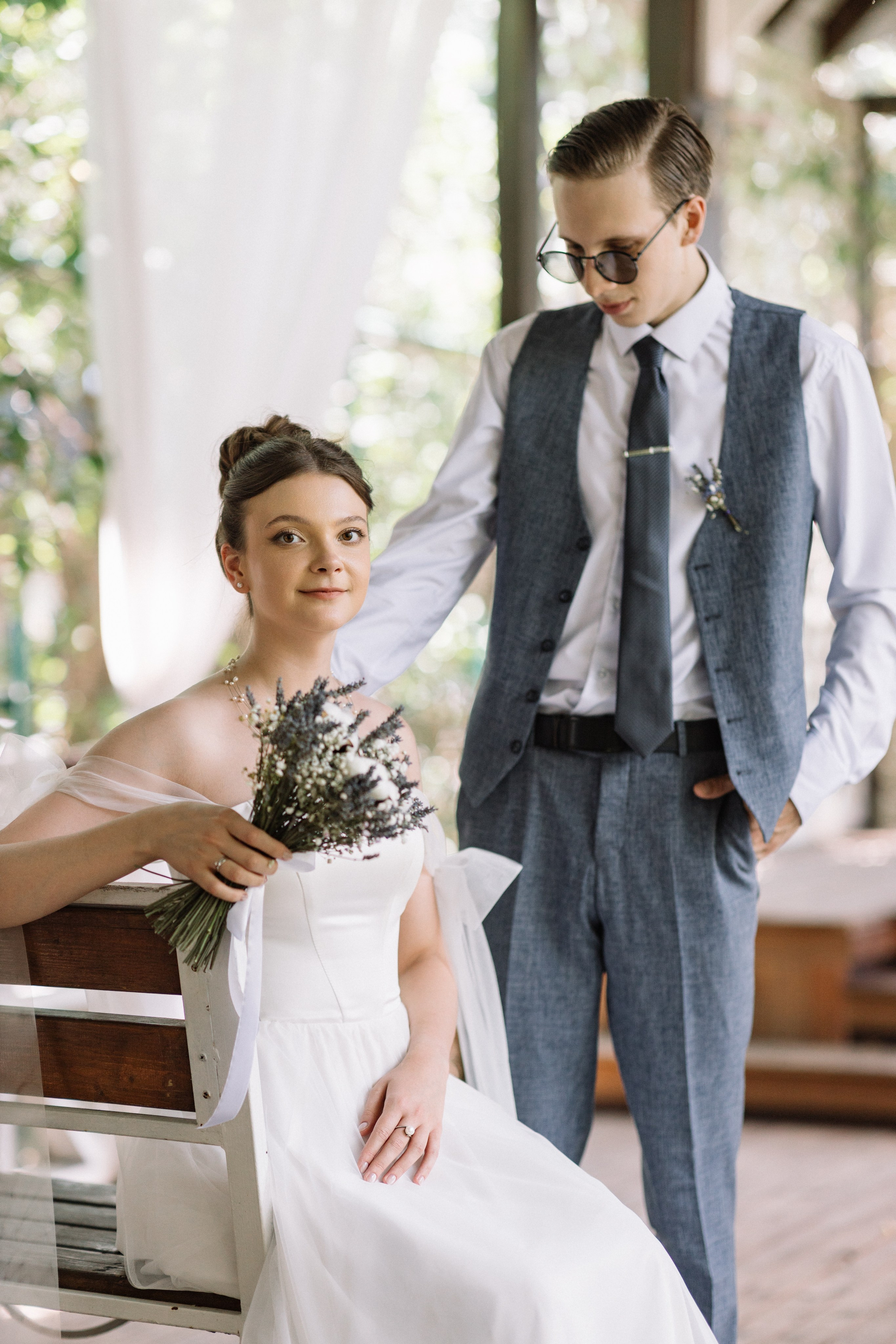 Юлия в белом платье с кружевами, Мартин в костюме, смотрят друг на друга на свадебной площадке.