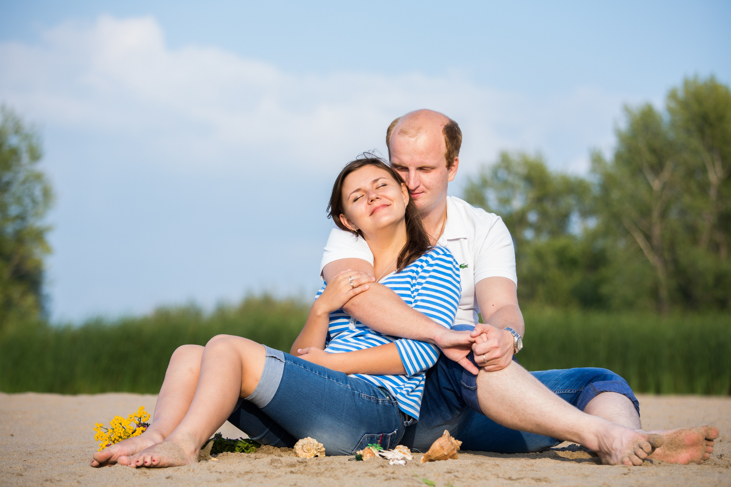 парень и девушка сидят в обнимку на песке