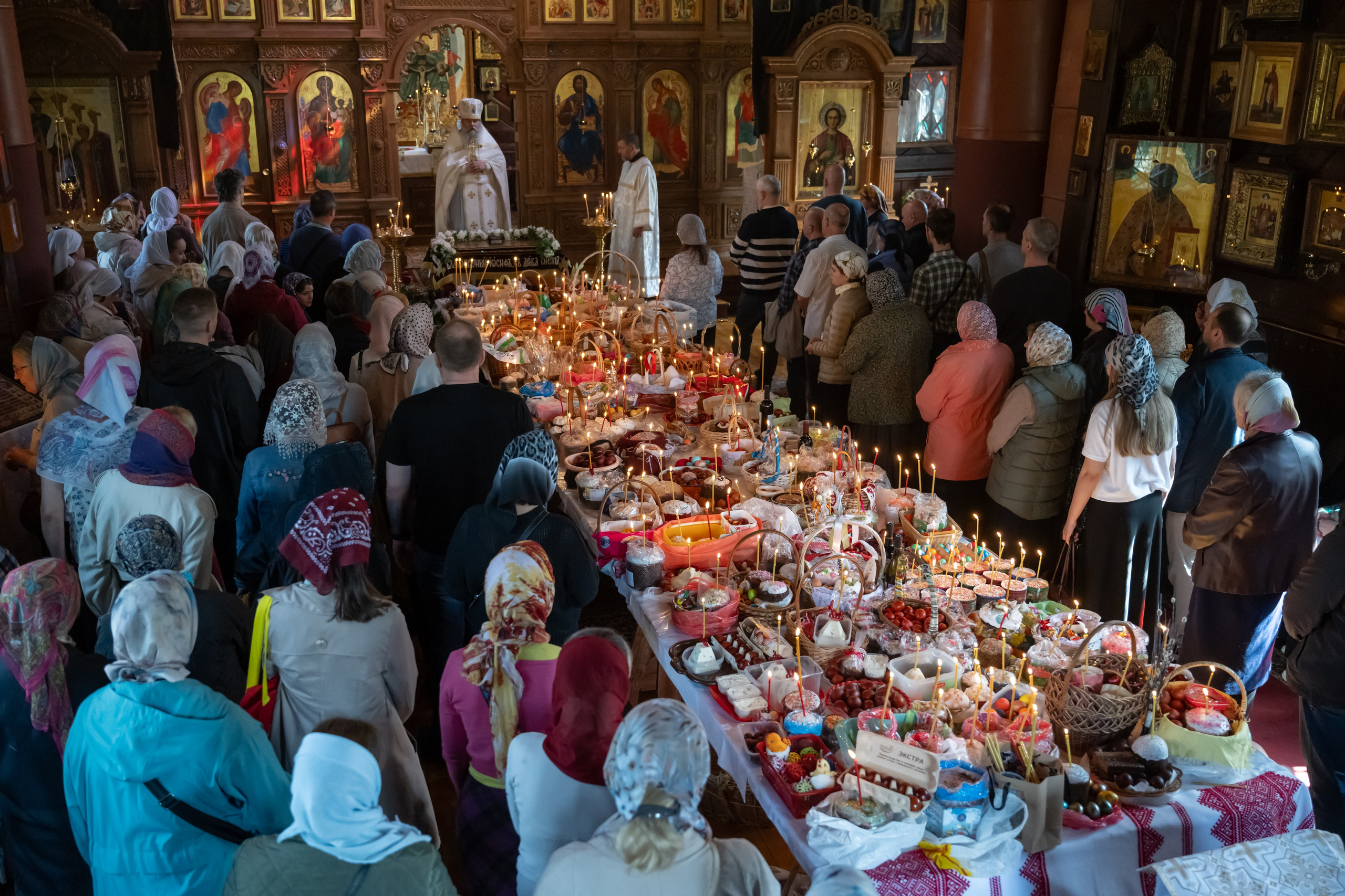 An Orthodox priest preaches to parishioners during the Easter service before blessing the Easter cakes and eggs arranged on tables in the church. St. Petersburg, April 19, 2025.
