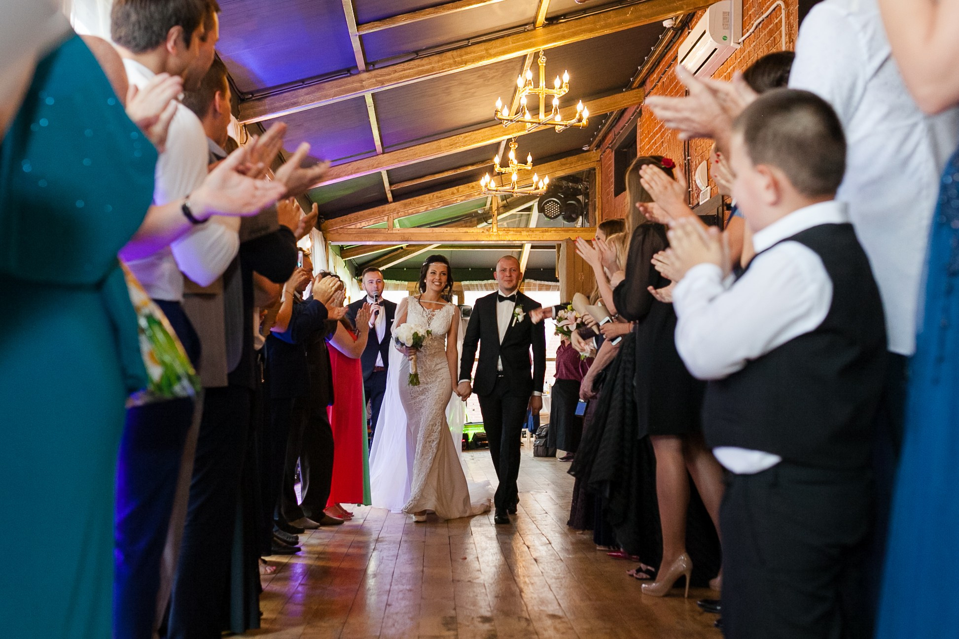 Жених и невеста идут сквозь в туннель из гостей