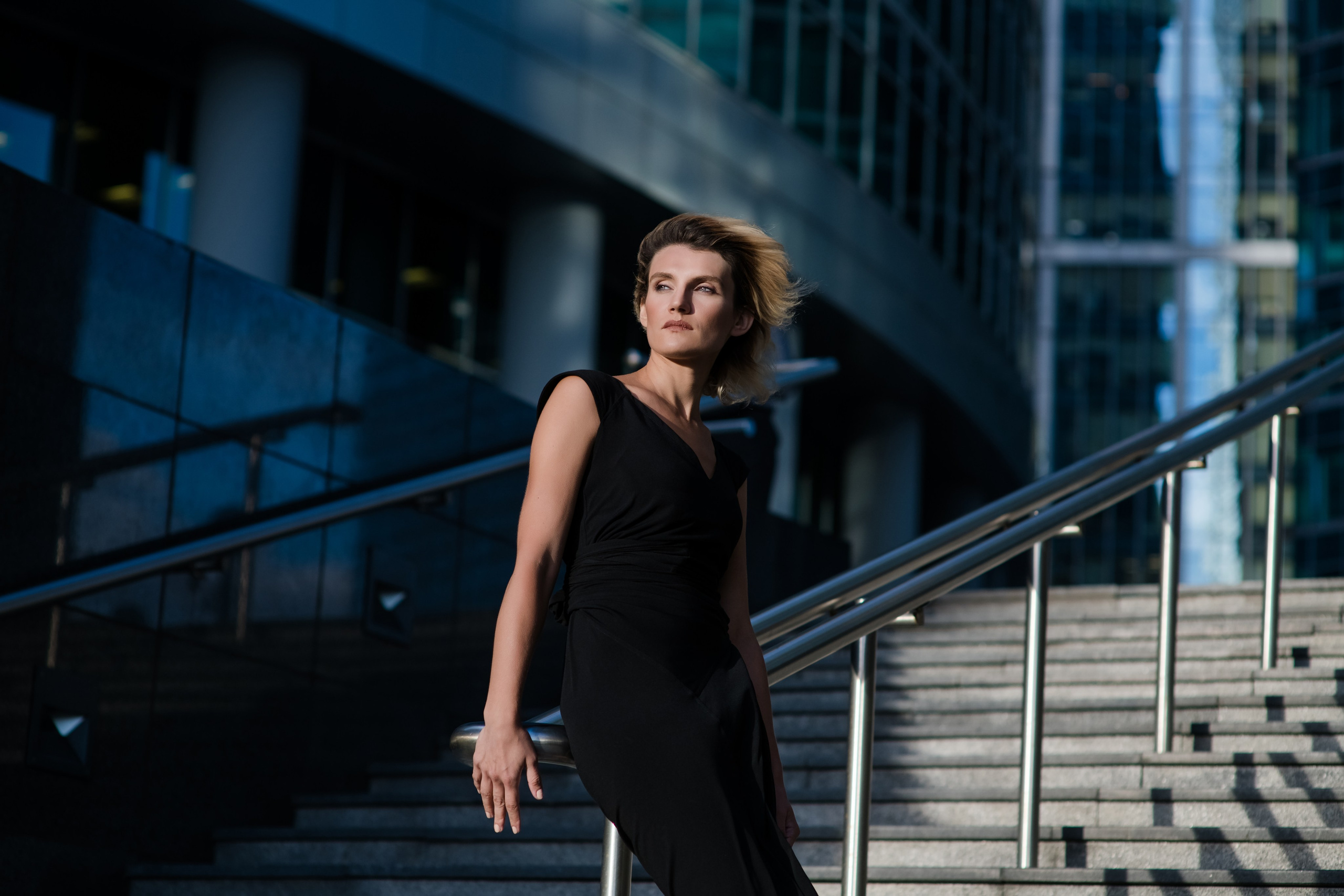 Девушка стоит на ветру на лестнице в комплексе Москва-Сити