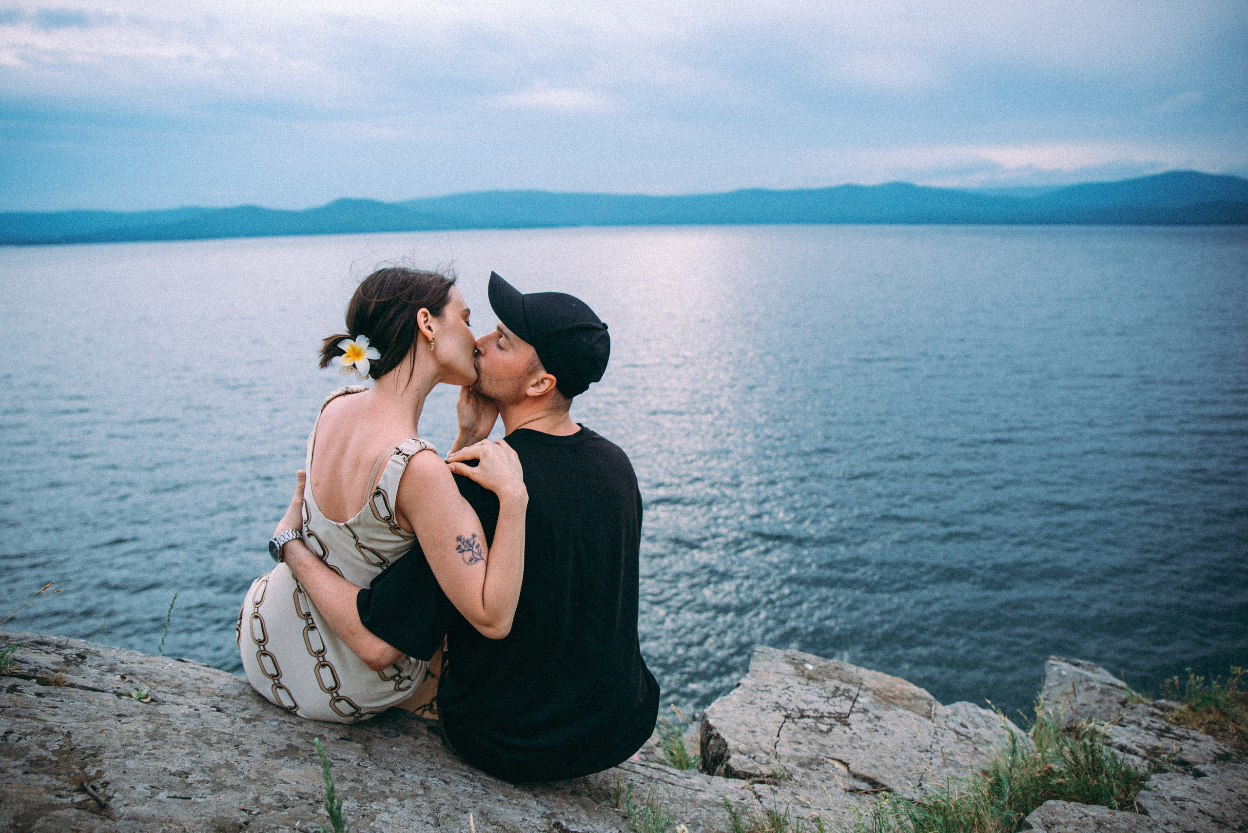 пара влюбленных целуется на берегу у обрыва