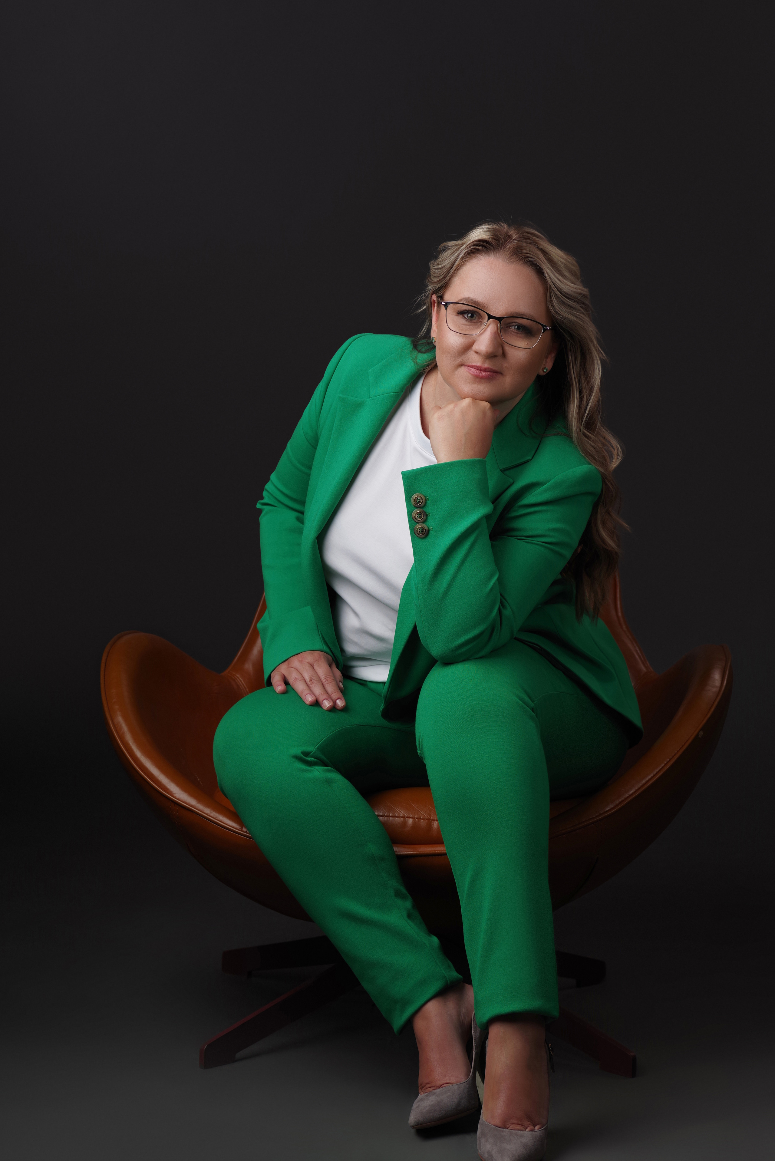 Портрет молодой женщины в зелёном костюме в кресле