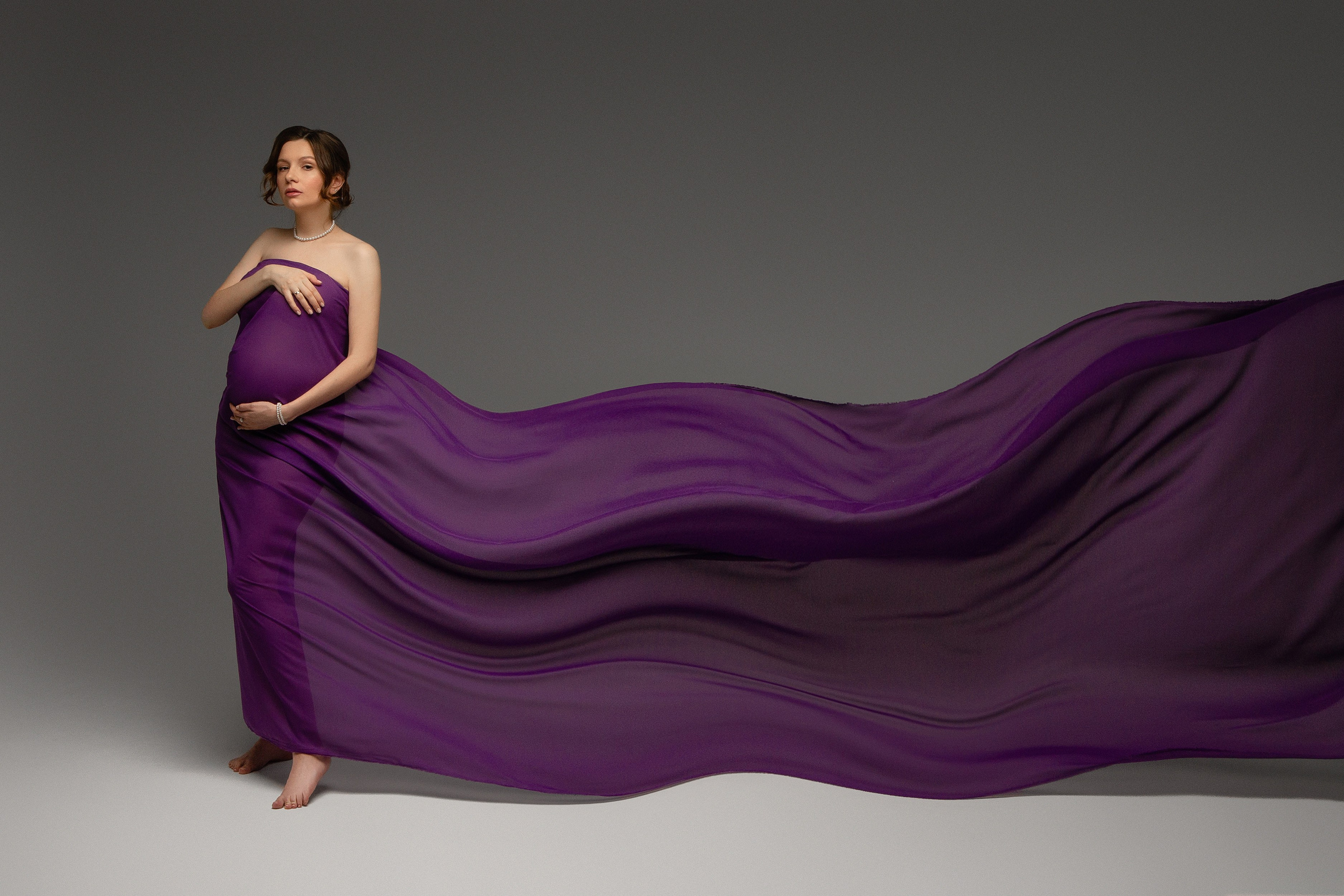 Беременная девушка в сиреневой ткани