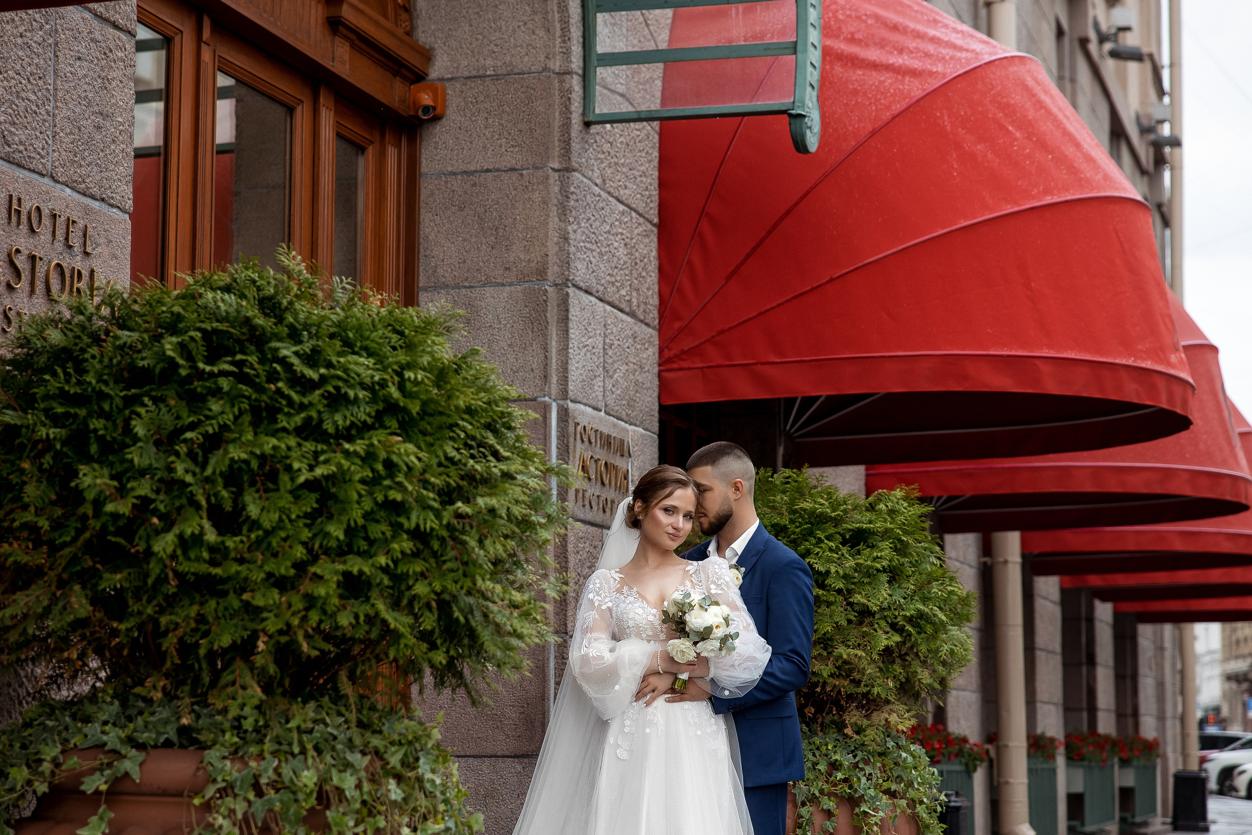 Портрет пары на фоне красных маркиз отеля Астория в Петербурге